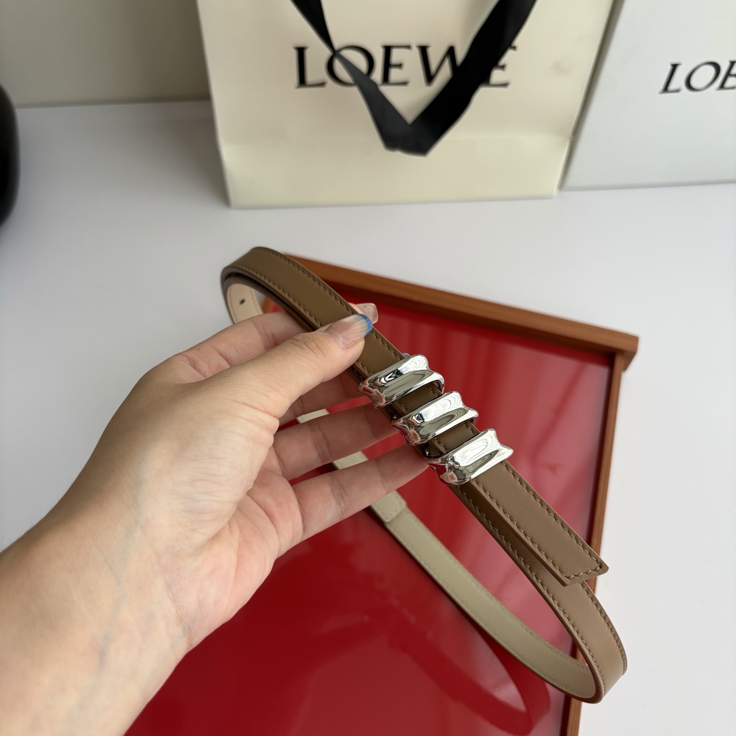 Loewe光滑牛皮革Coil双面腰带，饰有灵感源自品牌典藏的盘绕配件。Anchor腰带扣，宽1.5cm，五孔调节。摩卡色