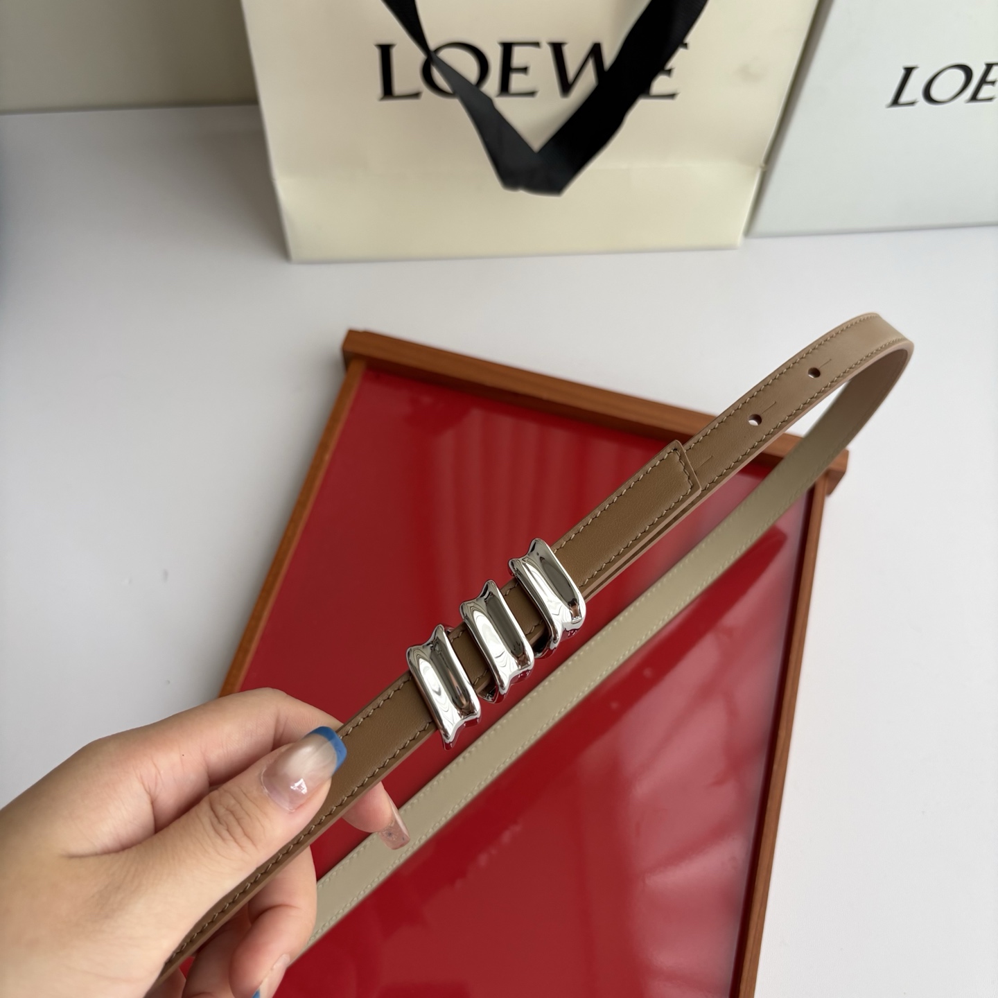 Loewe光滑牛皮革Coil双面腰带，饰有灵感源自品牌典藏的盘绕配件。Anchor腰带扣，宽1.5cm，五孔调节。摩卡色