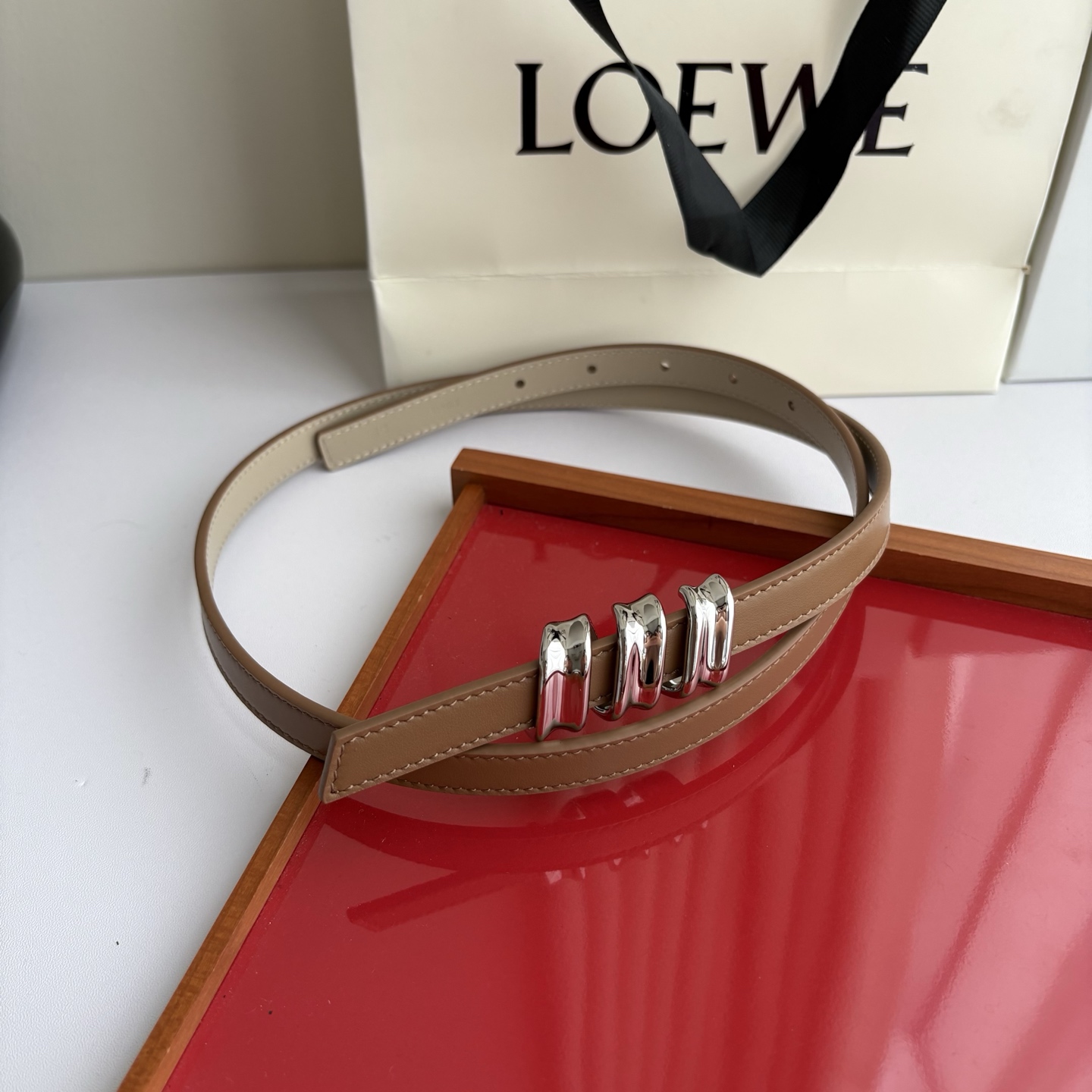 Loewe光滑牛皮革Coil双面腰带，饰有灵感源自品牌典藏的盘绕配件。Anchor腰带扣，宽1.5cm，五孔调节。摩卡色