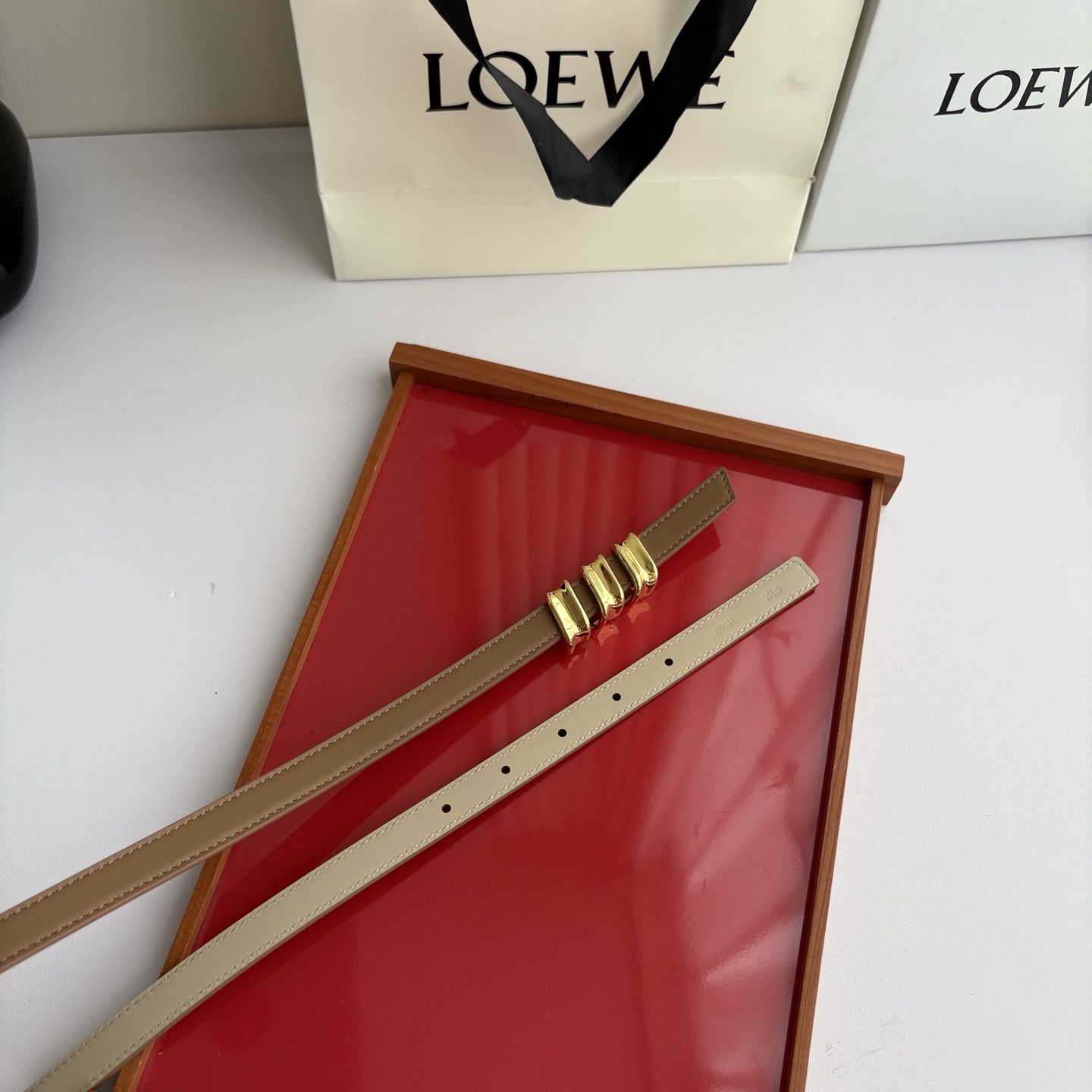 Loewe光滑牛皮革Coil双面腰带，饰有灵感源自品牌典藏的盘绕配件。Anchor腰带扣，宽1.5cm，五孔调节。摩卡色