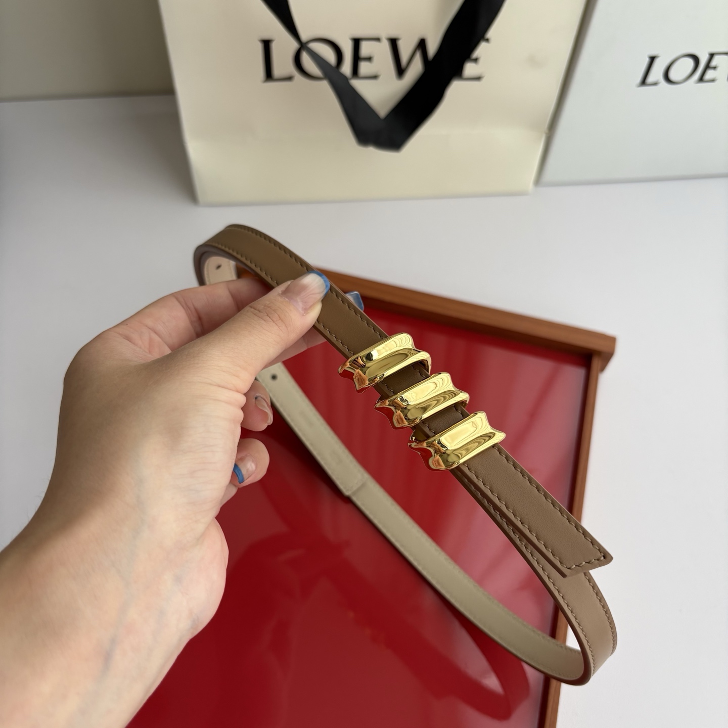 Loewe光滑牛皮革Coil双面腰带，饰有灵感源自品牌典藏的盘绕配件。Anchor腰带扣，宽1.5cm，五孔调节。摩卡色