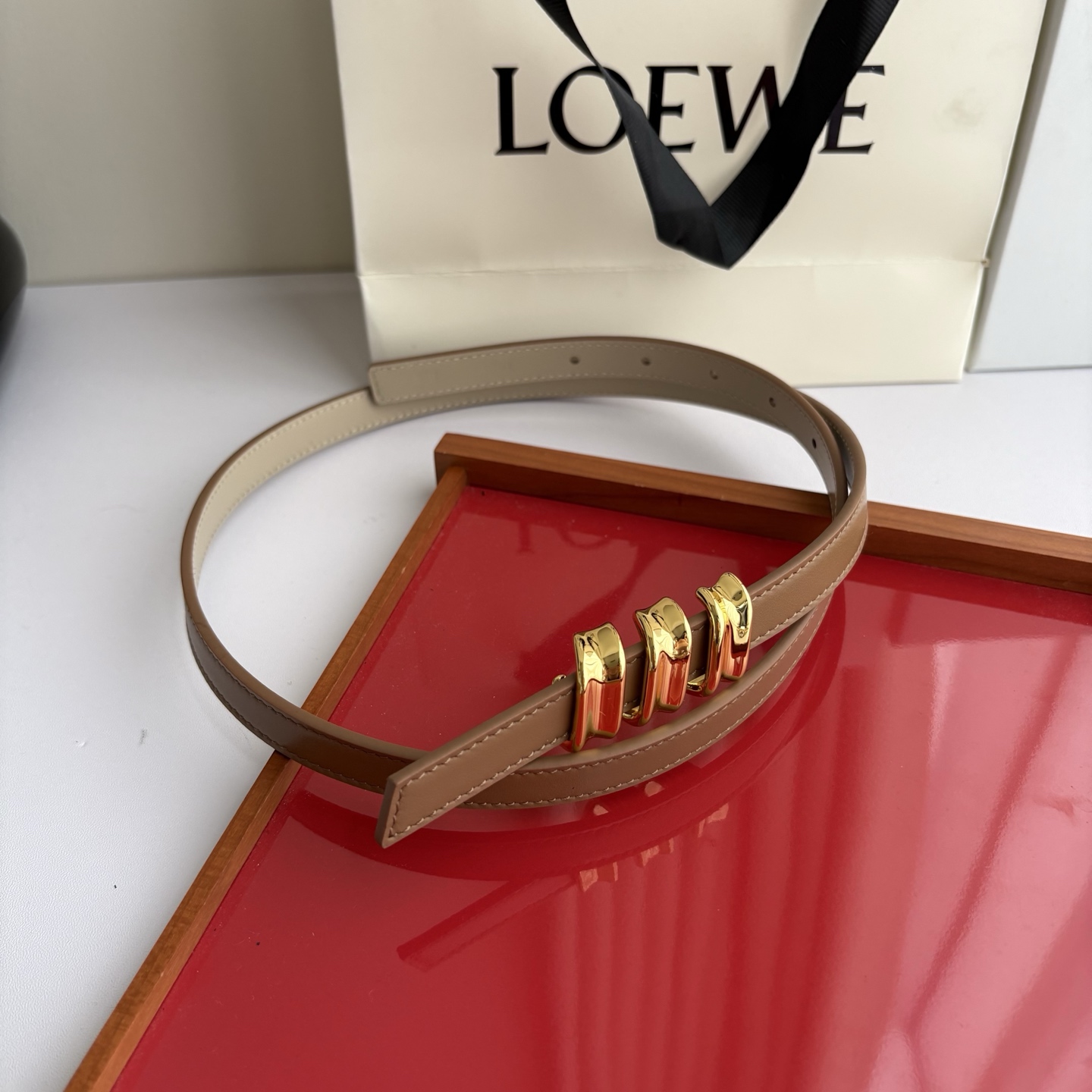 Loewe光滑牛皮革Coil双面腰带，饰有灵感源自品牌典藏的盘绕配件。Anchor腰带扣，宽1.5cm，五孔调节。摩卡色