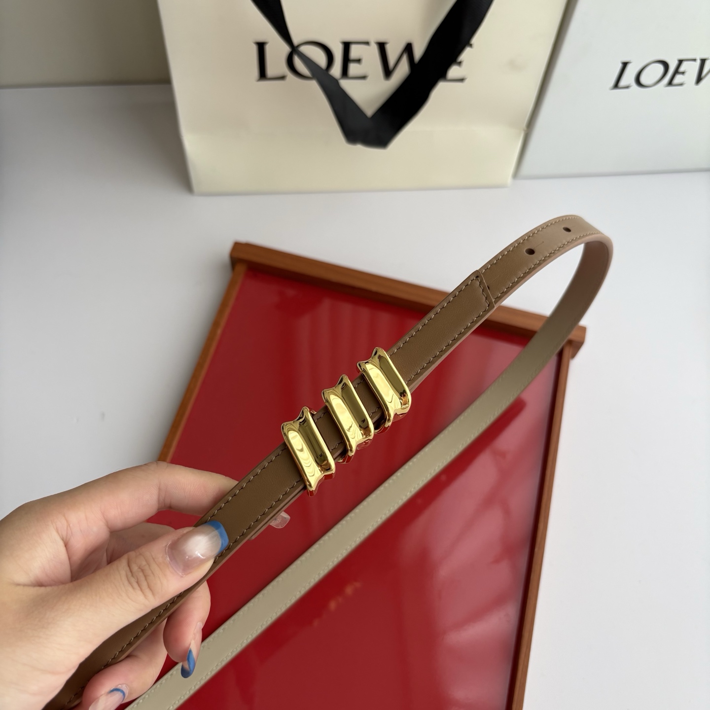 Loewe光滑牛皮革Coil双面腰带，饰有灵感源自品牌典藏的盘绕配件。Anchor腰带扣，宽1.5cm，五孔调节。摩卡色