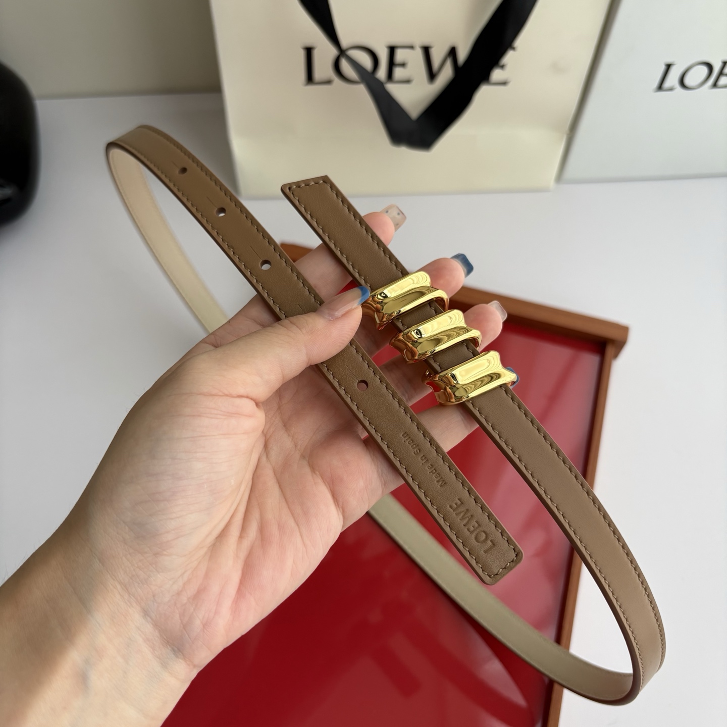 Loewe光滑牛皮革Coil双面腰带，饰有灵感源自品牌典藏的盘绕配件。Anchor腰带扣，宽1.5cm，五孔调节。摩卡色