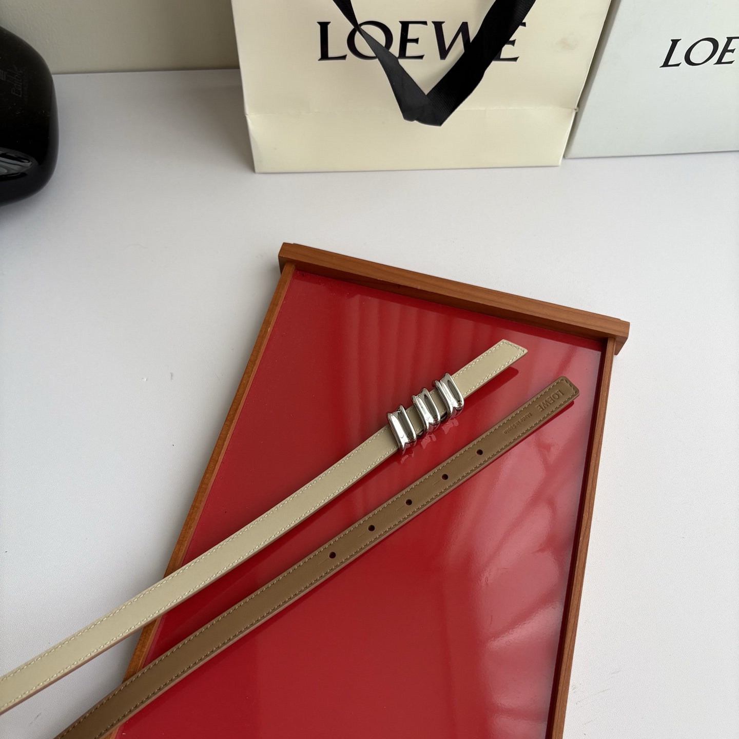 Loewe光滑牛皮革Coil双面腰带，饰有灵感源自品牌典藏的盘绕配件。Anchor腰带扣，宽1.5cm，五孔调节。摩卡色