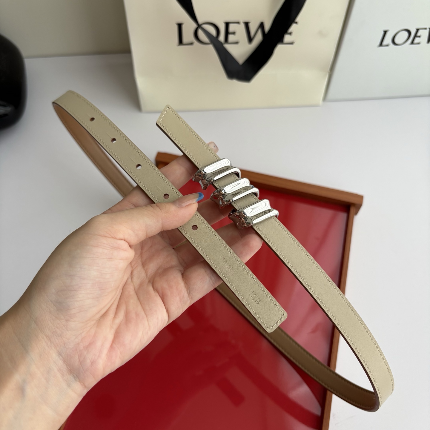 Loewe光滑牛皮革Coil双面腰带，饰有灵感源自品牌典藏的盘绕配件。Anchor腰带扣，宽1.5cm，五孔调节。摩卡色