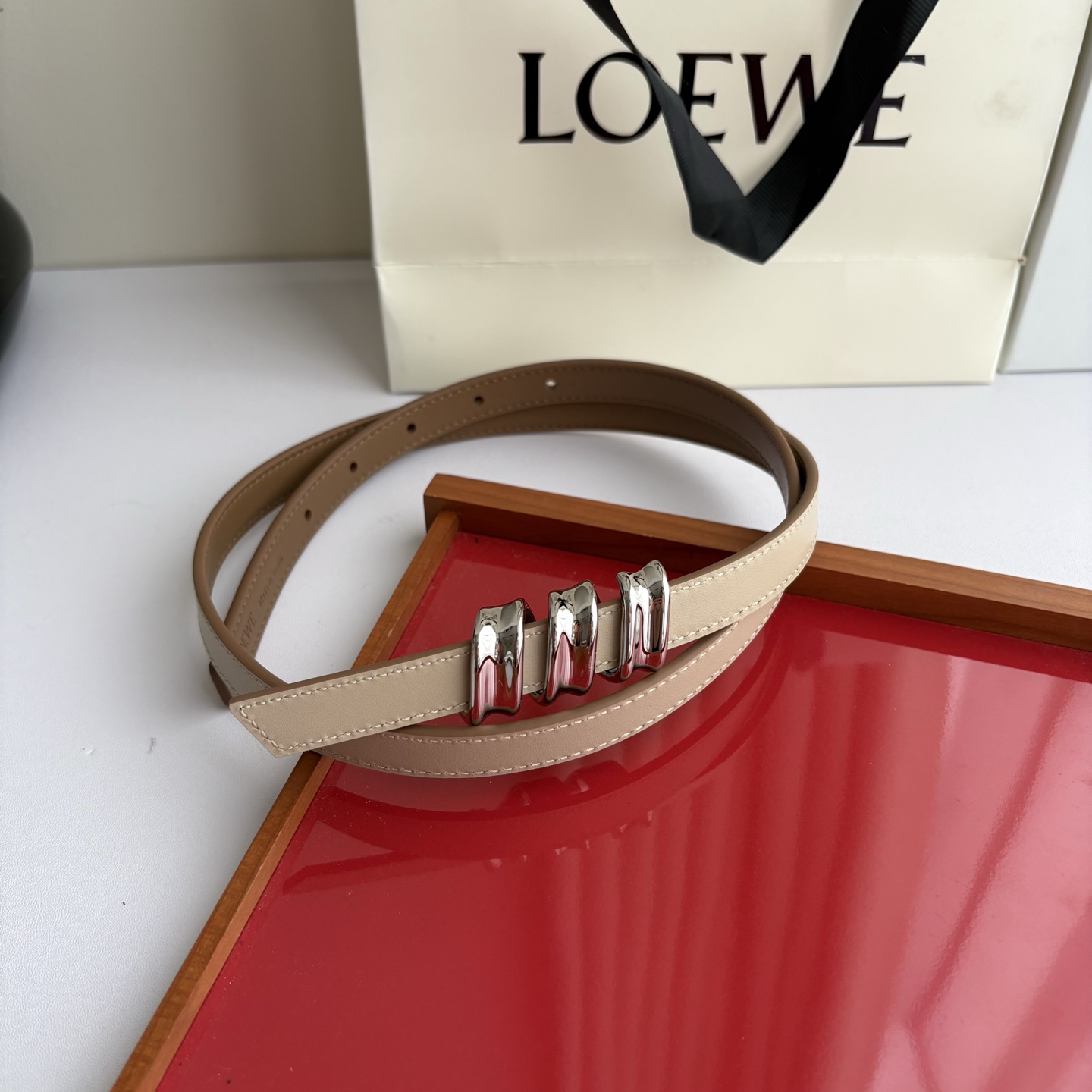 Loewe光滑牛皮革Coil双面腰带，饰有灵感源自品牌典藏的盘绕配件。Anchor腰带扣，宽1.5cm，五孔调节。摩卡色