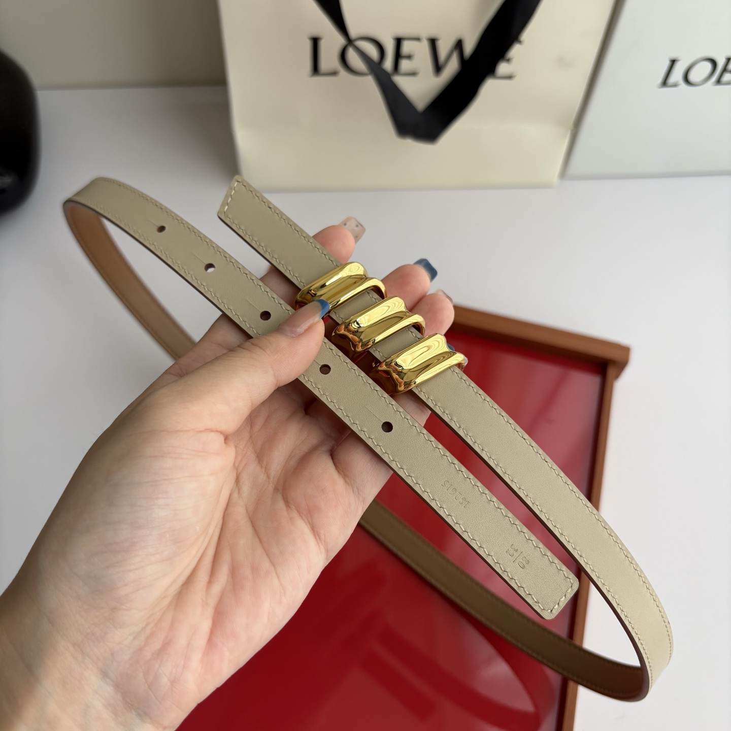 Loewe光滑牛皮革Coil双面腰带，饰有灵感源自品牌典藏的盘绕配件。Anchor腰带扣，宽1.5cm，五孔调节。摩卡色