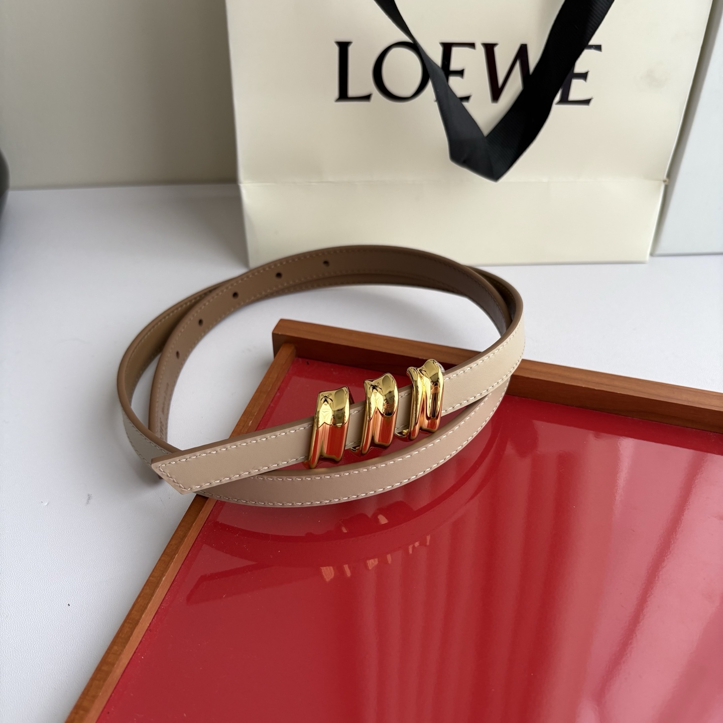 Loewe光滑牛皮革Coil双面腰带，饰有灵感源自品牌典藏的盘绕配件。Anchor腰带扣，宽1.5cm，五孔调节。摩卡色