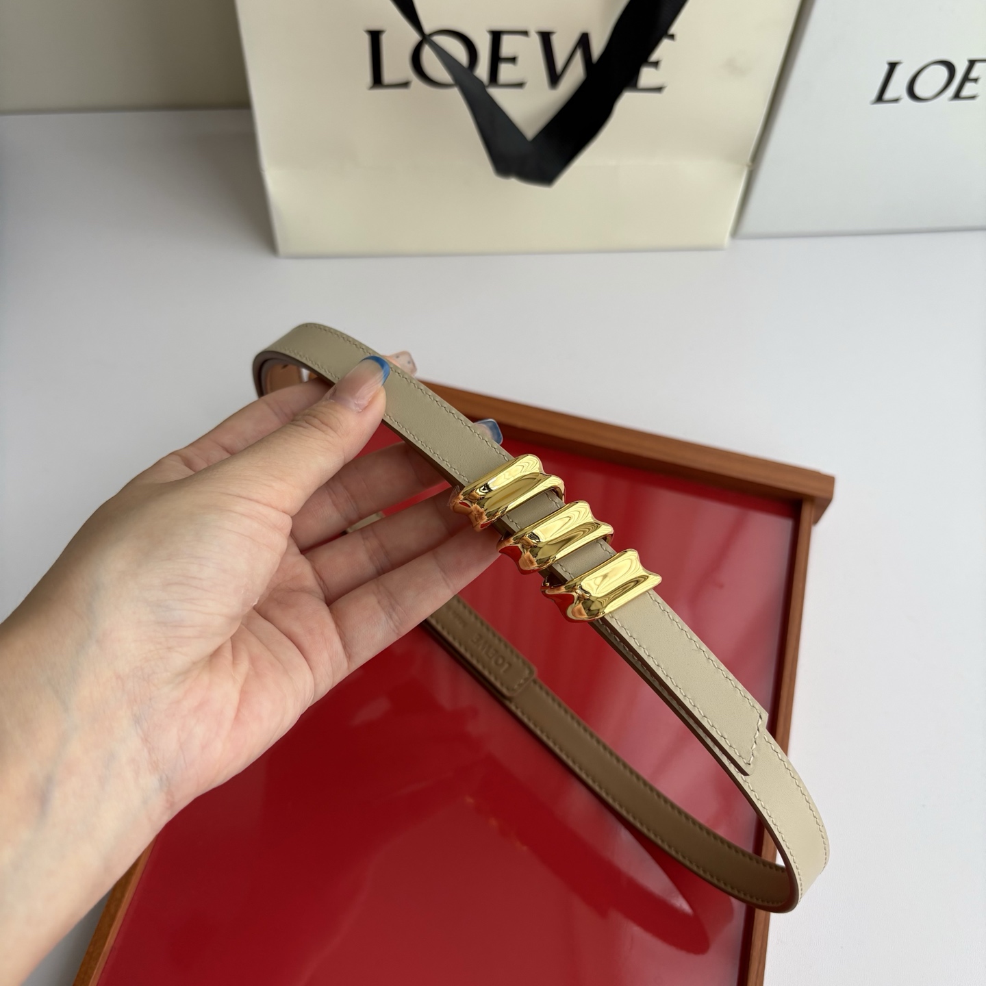 Loewe光滑牛皮革Coil双面腰带，饰有灵感源自品牌典藏的盘绕配件。Anchor腰带扣，宽1.5cm，五孔调节。摩卡色
