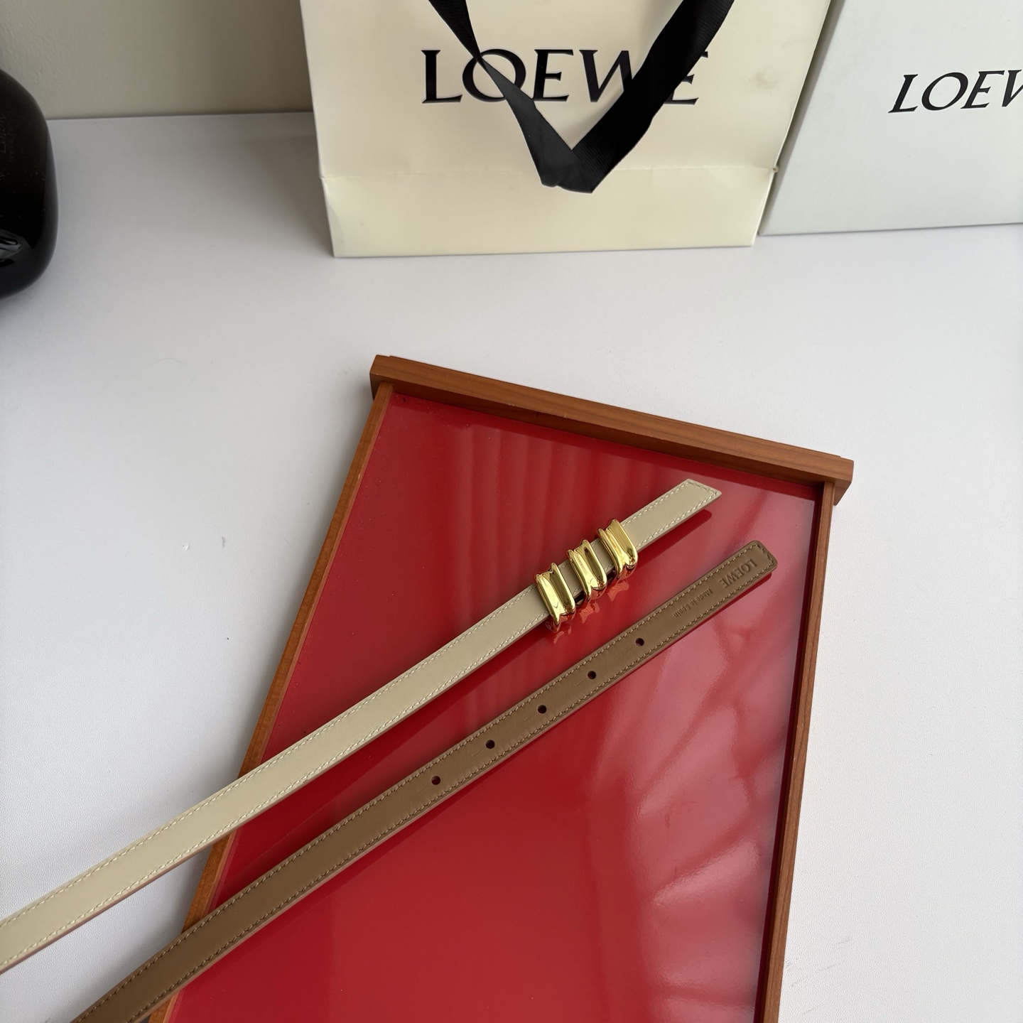 Loewe光滑牛皮革Coil双面腰带，饰有灵感源自品牌典藏的盘绕配件。Anchor腰带扣，宽1.5cm，五孔调节。摩卡色