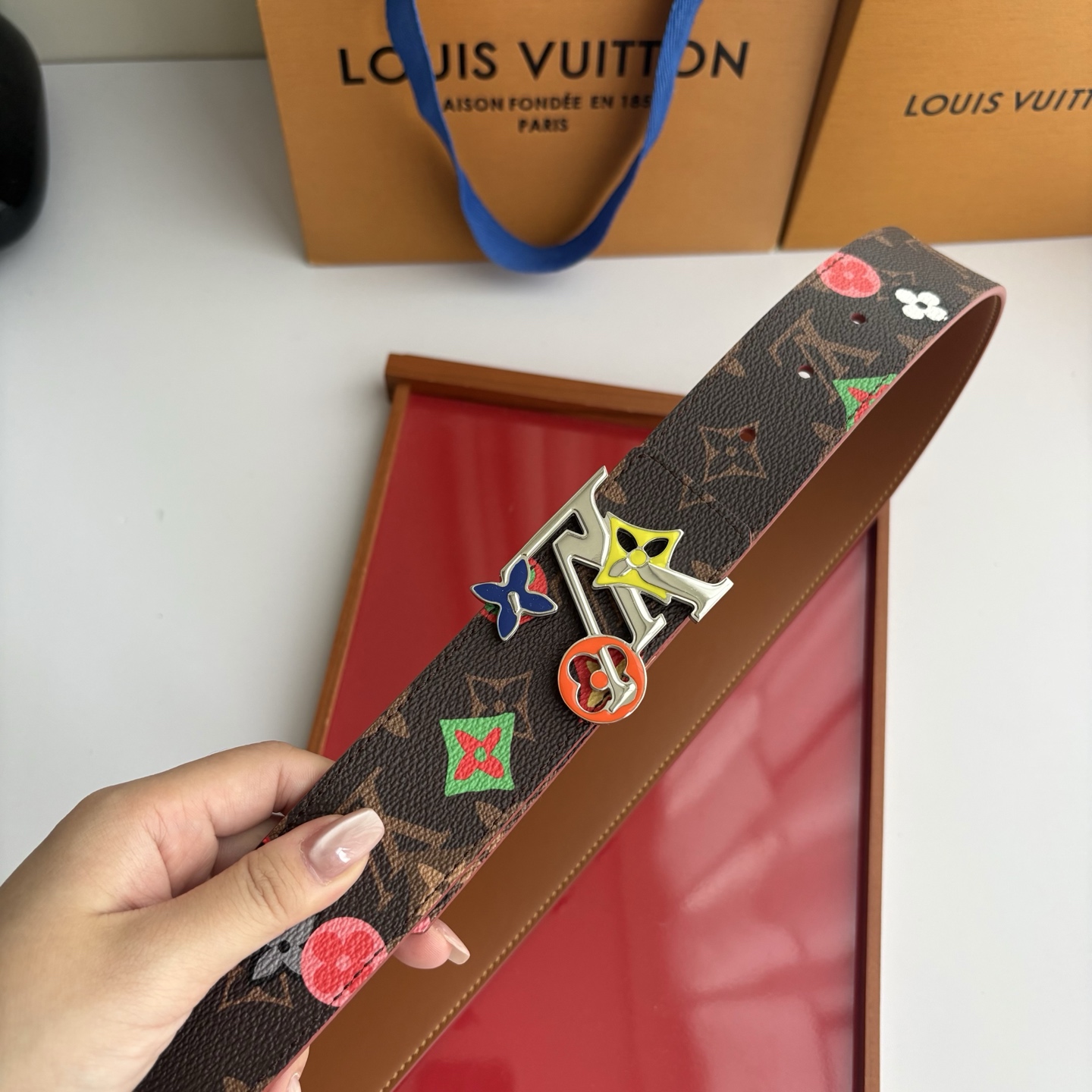 Lv当季新款，经典老花底色，叠加粉、绿、红彩色四花涂鸦印花，两面切换佩戴。正面彩色限定印花帆布；反面棕褐色光滑牛皮。宽4