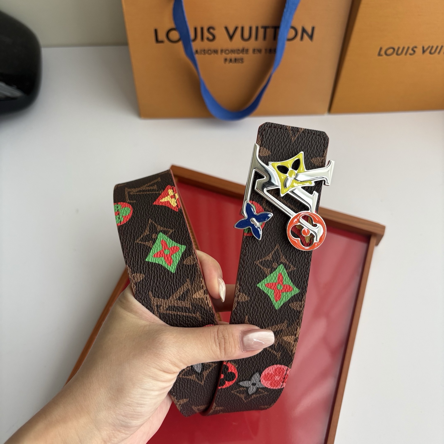 Lv当季新款，经典老花底色，叠加粉、绿、红彩色四花涂鸦印花，两面切换佩戴。正面彩色限定印花帆布；反面棕褐色光滑牛皮。宽4