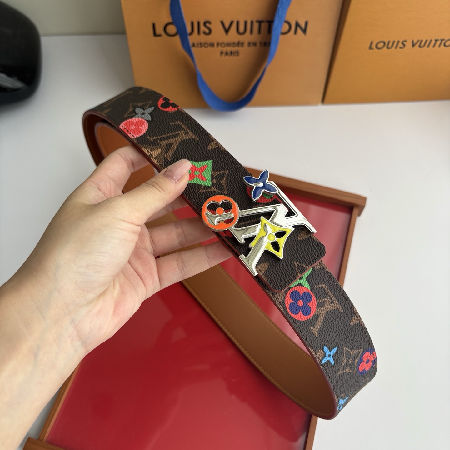 Lv当季新款，经典老花底色，叠加粉、绿、红彩色四花涂鸦印花，两面切换佩戴。正面彩色限定印花帆布；反面棕褐色光滑牛皮。宽4