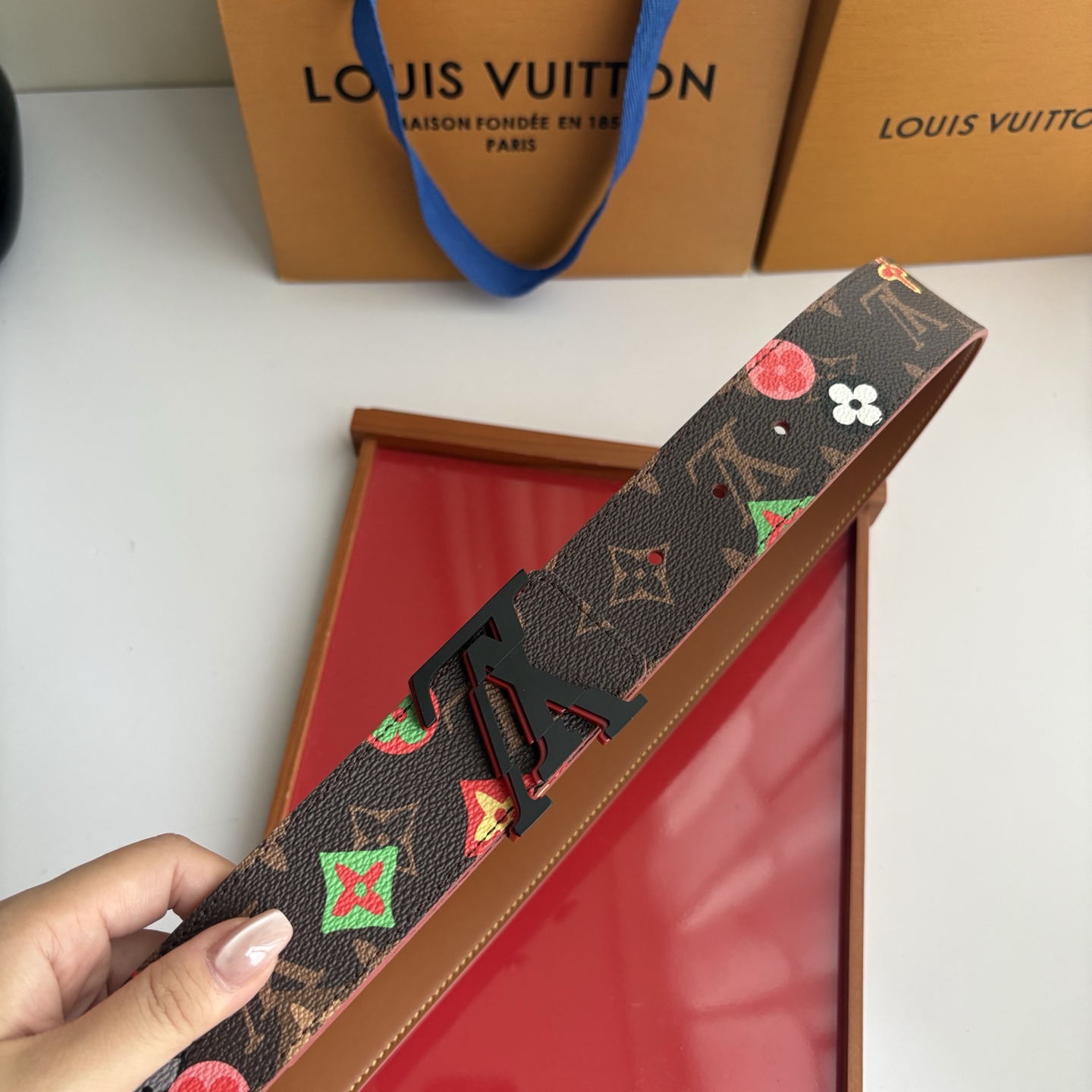 Lv当季新款，经典老花底色，叠加粉、绿、红彩色四花涂鸦印花，两面切换佩戴。正面彩色限定印花帆布；反面棕褐色光滑牛皮。宽4