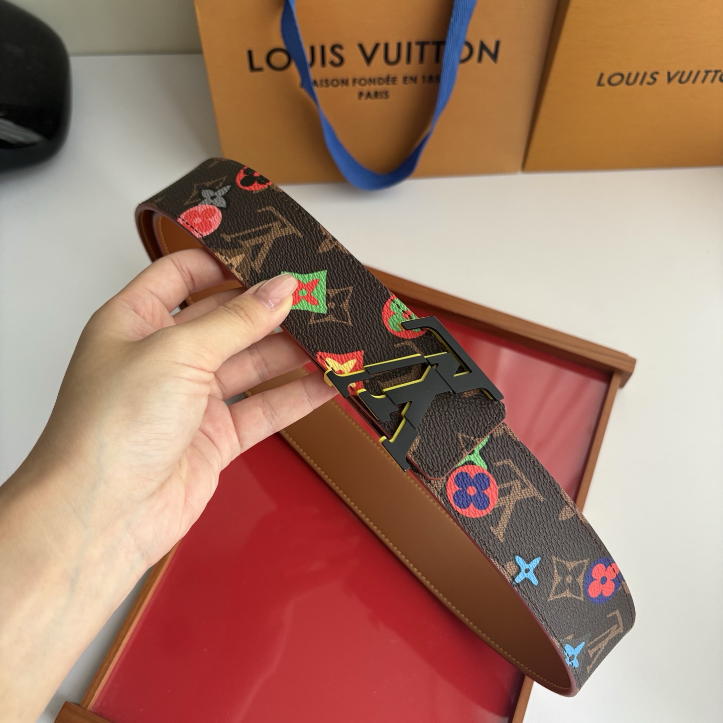 Lv当季新款，经典老花底色，叠加粉、绿、红彩色四花涂鸦印花，两面切换佩戴。正面彩色限定印花帆布；反面棕褐色光滑牛皮。宽4