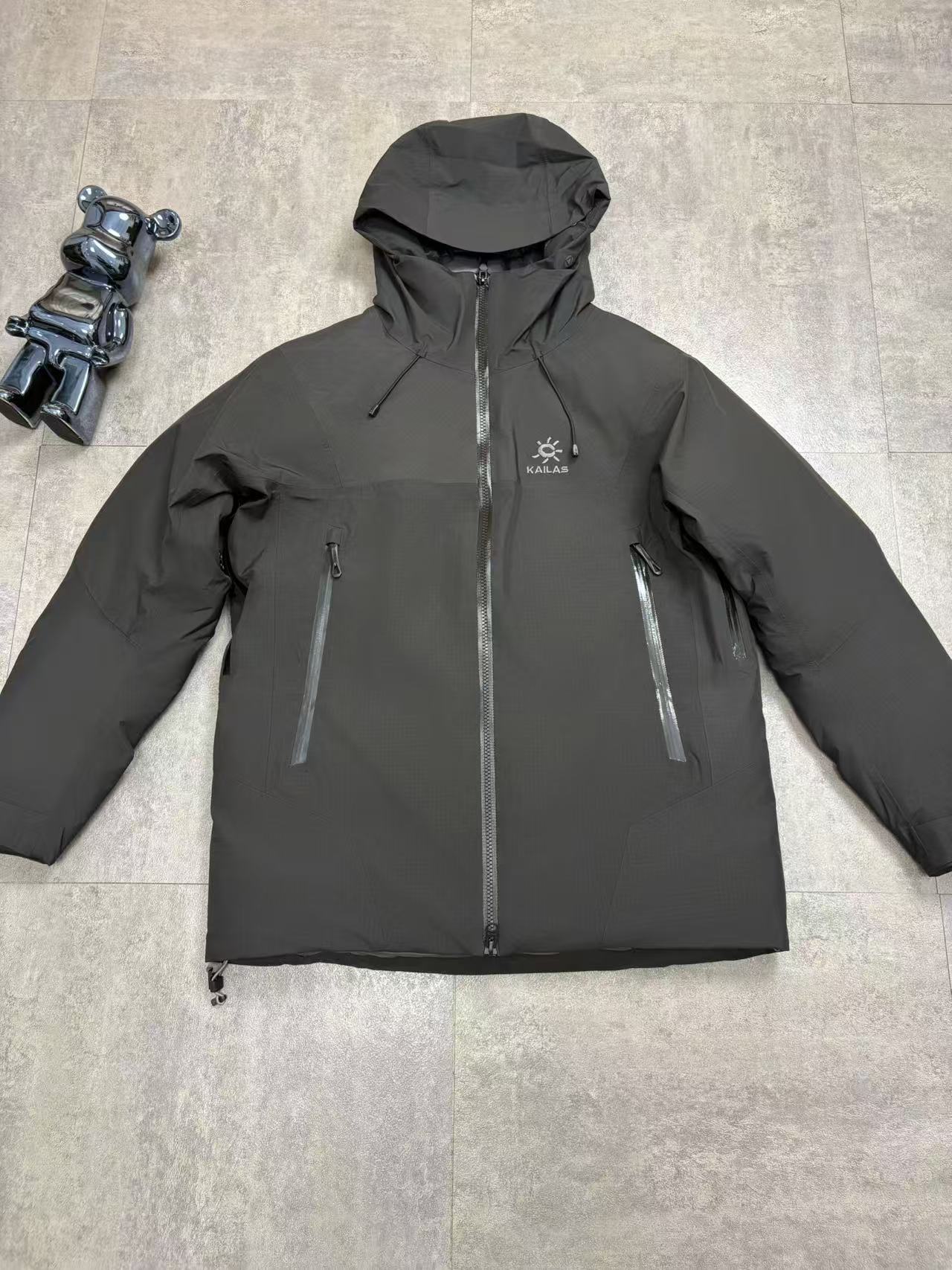 💰480
顶级版本 KAILAS/阿斯本硬壳羽绒服男女同款加厚外套情侣款滑雪服登山徒步必备
外贸专供的国标90绒版本，随意对比
保暖性、防护性、舒适性等方面都超赞😬适合户外爱好者在冬季进行滑雪、徒步、登山
等活动时穿着也适用于日常的通勤和出差旅行
防风防水性强，采用FILTER-TEC 3 层硬壳面料，这种面料的防风、防水性能优异，里面接缝全压胶，能够有效抵御冬季的风雨雪天气，适合在较为恶劣的户外环境中穿着，为穿着者提供可靠的防护。
格子布耐磨性较好：硬壳面料通常具有一定的耐磨性，在户外活动中可以减少因摩擦等因素对羽绒服造成的损坏，延长其使用寿命。
羽绒填充蓬松度高：填充 700 蓬的鹅绒，蓬松度较高。在相同重量下，蓬松度越高的羽绒可以固定更多的空气，从而形成更好的隔热层，保暖性能也就越好。
绒子含量高：鹅绒的绒子含量达到 90%，绒子含量高意味着羽绒的质量好，保暖效果更出色，同时也能减少羽绒在使用过程中的结块现象，保持羽绒服的蓬松度和保暖性。
保暖科技采用石墨烯热反射：内里添加了石墨烯热反射科技，能够加强核心区的保暖。石墨烯具有良好的导热性和热反射性，可以将人体散发的热量反射回身体，提高保暖效果，在寒冷的环境中能够更好地保持身体的温暖。
风帽设计：风帽三维可调节，贴合头部，能够有效防风保暖，为头部提供额外的保护，在寒冷的天气中可以减少头部的热量散失。
袖口设计：采用魔术贴袖口，可以根据个人的需求进行调节，增强袖口的密封性，防止寒风从袖口侵入。
腋下透气拉链：配备腋下透气拉链，方便在运动过程中调节体温，避免因身体发热而产生闷热感，提高穿着的舒适性。
口袋设计：多口袋设计，方便使用者存放随身物品，如手机、钥匙、钱包等，使物品摆放井然有序，方便取用

颜色：黑色  浅云灰 

尺码：S-XXL
衣长：76 78 80 82 84
胸围：122 126 130 134 138
肩宽：49 50 51 52 54
袖长：67 68 69 70 71
s建议110斤以下
m建议110-130
L建议130-150
xl建议150—170
xxl建议170-195斤
         