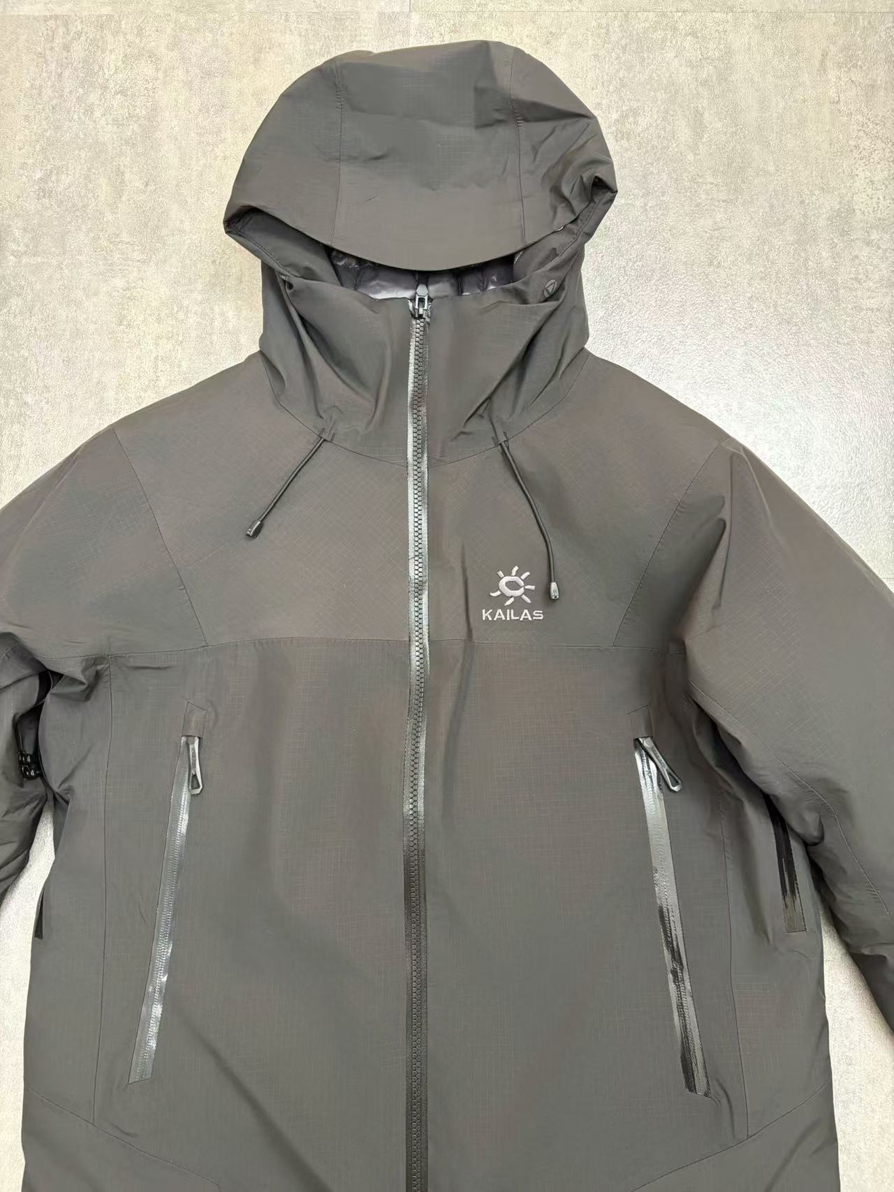 💰480
顶级版本 KAILAS/阿斯本硬壳羽绒服男女同款加厚外套情侣款滑雪服登山徒步必备
外贸专供的国标90绒版本，随意对比
保暖性、防护性、舒适性等方面都超赞😬适合户外爱好者在冬季进行滑雪、徒步、登山
等活动时穿着也适用于日常的通勤和出差旅行
防风防水性强，采用FILTER-TEC 3 层硬壳面料，这种面料的防风、防水性能优异，里面接缝全压胶，能够有效抵御冬季的风雨雪天气，适合在较为恶劣的户外环境中穿着，为穿着者提供可靠的防护。
格子布耐磨性较好：硬壳面料通常具有一定的耐磨性，在户外活动中可以减少因摩擦等因素对羽绒服造成的损坏，延长其使用寿命。
羽绒填充蓬松度高：填充 700 蓬的鹅绒，蓬松度较高。在相同重量下，蓬松度越高的羽绒可以固定更多的空气，从而形成更好的隔热层，保暖性能也就越好。
绒子含量高：鹅绒的绒子含量达到 90%，绒子含量高意味着羽绒的质量好，保暖效果更出色，同时也能减少羽绒在使用过程中的结块现象，保持羽绒服的蓬松度和保暖性。
保暖科技采用石墨烯热反射：内里添加了石墨烯热反射科技，能够加强核心区的保暖。石墨烯具有良好的导热性和热反射性，可以将人体散发的热量反射回身体，提高保暖效果，在寒冷的环境中能够更好地保持身体的温暖。
风帽设计：风帽三维可调节，贴合头部，能够有效防风保暖，为头部提供额外的保护，在寒冷的天气中可以减少头部的热量散失。
袖口设计：采用魔术贴袖口，可以根据个人的需求进行调节，增强袖口的密封性，防止寒风从袖口侵入。
腋下透气拉链：配备腋下透气拉链，方便在运动过程中调节体温，避免因身体发热而产生闷热感，提高穿着的舒适性。
口袋设计：多口袋设计，方便使用者存放随身物品，如手机、钥匙、钱包等，使物品摆放井然有序，方便取用

颜色：黑色  浅云灰 

尺码：S-XXL
衣长：76 78 80 82 84
胸围：122 126 130 134 138
肩宽：49 50 51 52 54
袖长：67 68 69 70 71
s建议110斤以下
m建议110-130
L建议130-150
xl建议150—170
xxl建议170-195斤
         