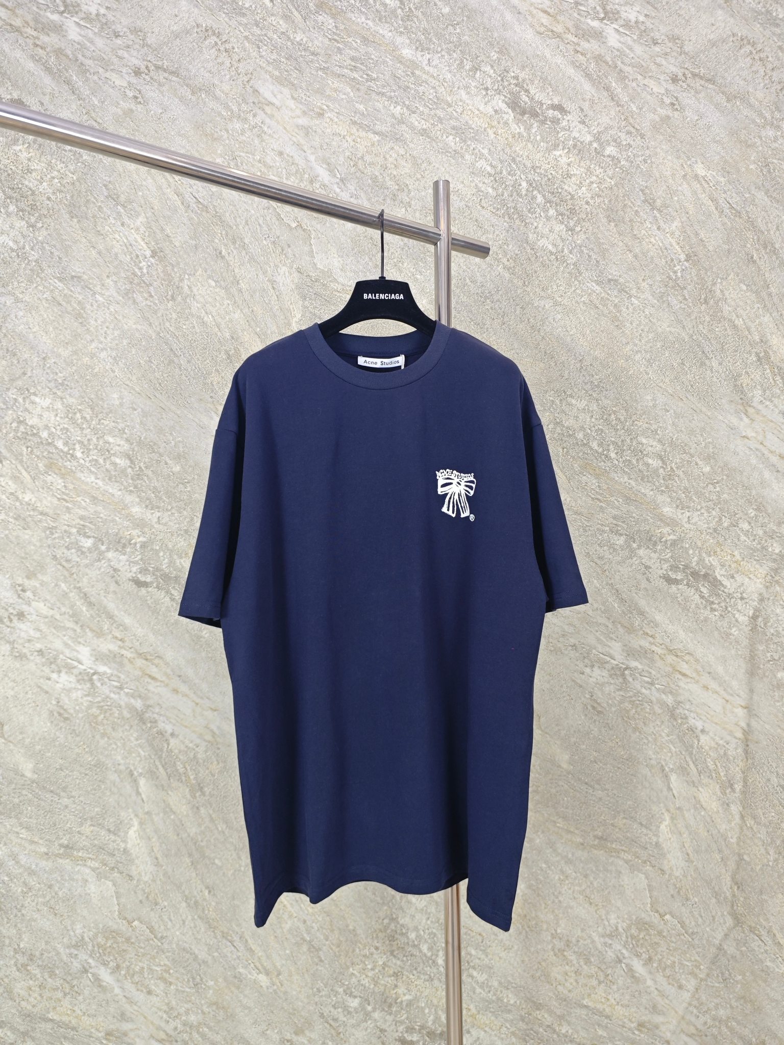 P130 도매 DM ACNE 보우 프린트 반팔 티셔츠. 스톡홀름에 기반을 둔 패션 브랜드 Acne Studios는 북유럽 미니멀리즘의 정수를 보여줍니다. 시크하고 절제된 스타일을 바탕으로 예술적인 세련미와 승화를 거듭하며 패션계의 트렌드세터로 자리매김했습니다. 이번 ACNE 2026 신상품은 레트로한 보우 프린트 반팔 티셔츠입니다. 루즈핏과 유니섹스 스타일은 시원하고 캐주얼한 분위기를 자아냅니다. 가슴 부분의 보우 프린트와 벽에 새겨진 듯한 Acne 레터링은 빈티지한 감성을 불러일으키며 고대 문화와 건축을 연상시킵니다. ACNE 브랜드명은 벽을 배경으로 더욱 어두운 색상으로 중앙에 강조되어 브랜드 인지도를 높였습니다. 화이트와 블랙 컬러의 조합은 풍부한 클래식감을 더하며 독특하고 트렌디한 룩을 완성합니다. 230g 워싱 코튼 소재로 제작되어 뛰어난 품질을 자랑합니다. 사이즈: (XS, S, M) 색상: 네이비 블루/그레이 1091