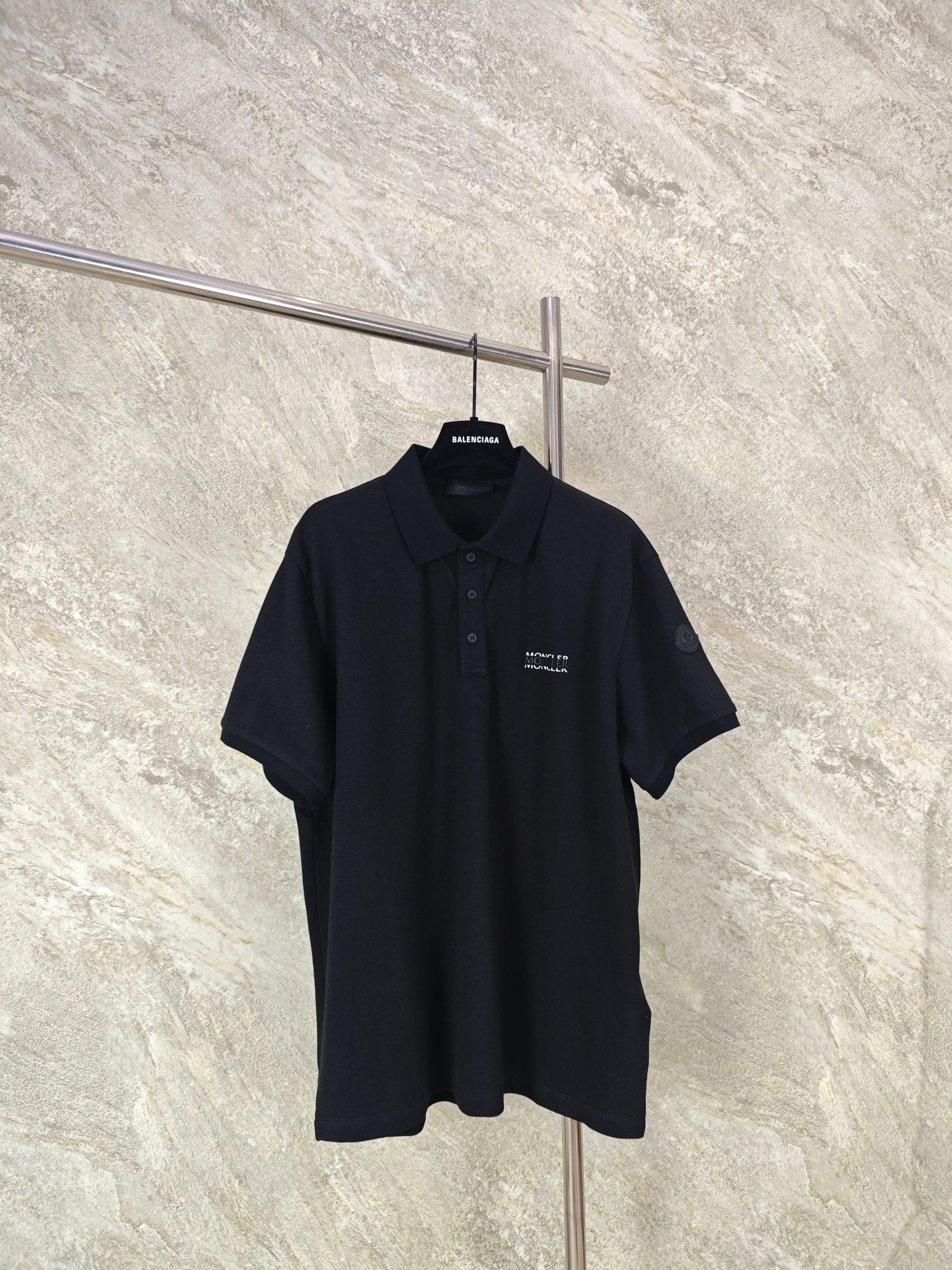 NO:824247,Top quality Moncler letter printed logo POLO shirt. Fabric selection: Precise blending of 48 cotton + 52 polyester fiber, with classic pique mesh knitting structure. It is a high-end fabric that takes into account natural skin-friendly and synthetic fiber properties.  .Cotton fiber provides the skin-friendly feel, moisture absorption and breathability of natural cotton, retains the soft texture of cotton, and avoids the sweat and itching problems of pure polyester fabrics; polyester fiber gives the fabric super wrinkle resistance, stiffness, abrasion resistance and quick-drying properties, solving the pain points of pure cotton being easy to wrinkle, deform, and difficult to care for; the bead structure further enhances the three-dimensionality, and the surface presents a regular concave and convex mesh shape, which structurally strengthens breathability. Printing process  High-elastic and environmentally friendly water-based PU thick version glue is selected, and through multiple overprinting + successive pre-baking processes. The black main layer is printed first, and is pre-baked at 80°C low temperature for each scraping print. Repeat three times to form a 0.5mm three-dimensional bulge in the glue. Size: SMLXL, mask-clothing, Moncler,19860909顶级品质 Moncler字母印花标识POLO衫 面料选择 采用48棉+52聚酯纤维的精准混纺,搭配经典珠地网眼针织结构,兼顾天然亲肤与合成纤维性能的高端面料 .棉纤维提供天然棉的亲肤感、吸湿透气性,保留棉的柔软质感,避免纯涤面料的闷汗、刺痒问题；聚酯纤维赋予面料超强的抗皱性、挺括度、耐磨度与速干性,解决纯棉易皱、易变形、难打理的痛点；珠地结构进一步提升立体度,表面呈现规则的凹凸网眼状,从结构上强化了透气性. 印花工艺 选用高弹环保水性PU厚版胶浆,通过多次叠印+逐次预烘工艺.先印黑色主体层,每刮印一次就进行80℃低温预烘定型,重复3次让胶浆形成0.5mm的立体凸起. Size:SMLXL,蒙口-服装,Moncler,,Women's clothing