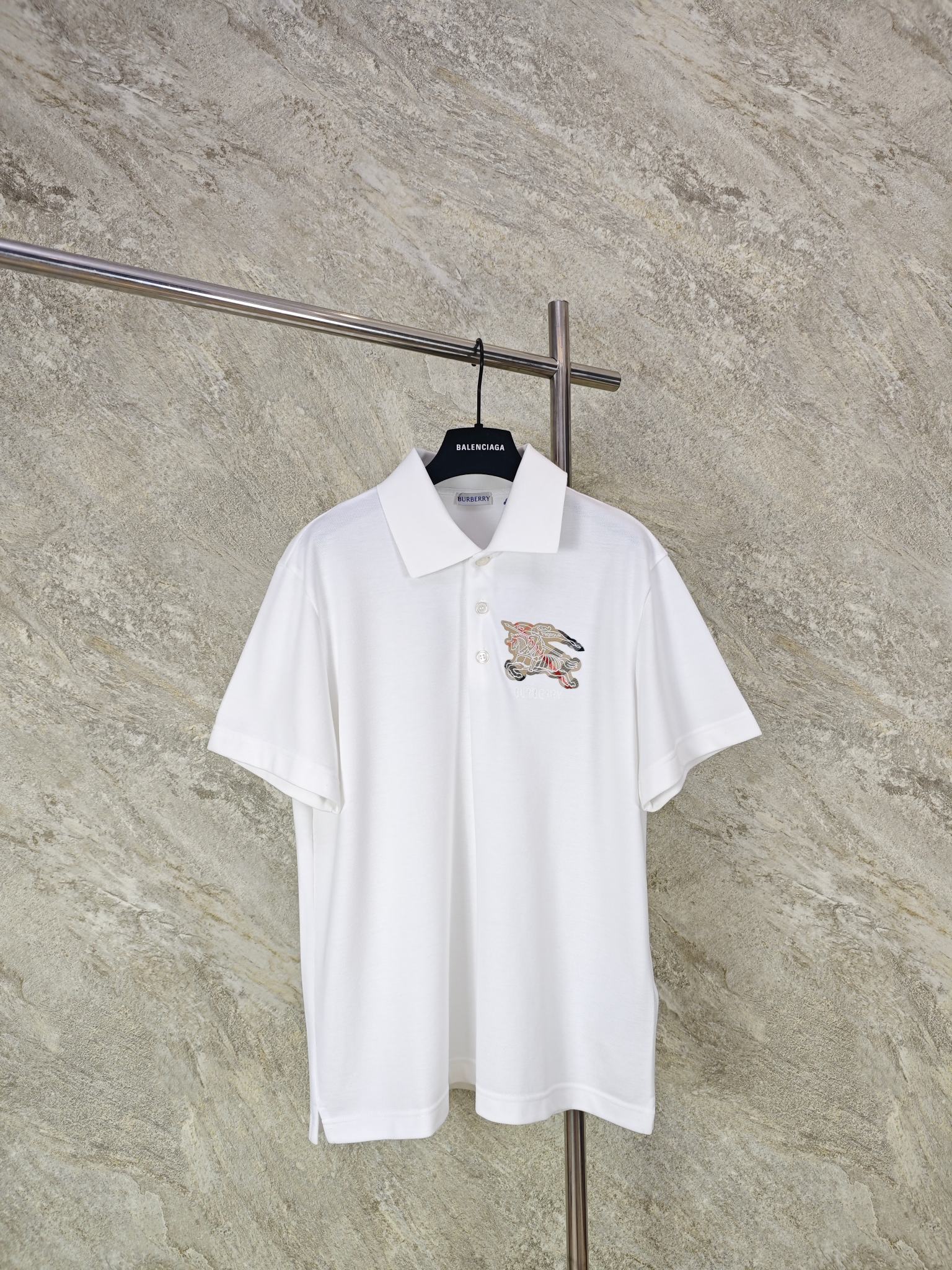 NO:824258,Top quality BURBERRY war horse appliqué embroidered POLO shirt. Fabric selection: Precise blending of 48 cotton + 52 polyester fiber, with classic pique mesh knitting structure. It is a high-end fabric that takes into account natural skin-friendly and synthetic fiber properties.  .Cotton fiber provides the skin-friendly feel, moisture absorption and breathability of natural cotton, retains the soft texture of cotton, and avoids the sweat and itching problems of pure polyester fabrics; polyester fiber gives the fabric super wrinkle resistance, stiffness, abrasion resistance and quick-drying properties, solving the pain points of pure cotton that is easy to wrinkle, deform, and be difficult to care for; the bead structure further enhances the three-dimensionality, and the surface presents a regular concave and convex mesh shape, which structurally strengthens the breathability. Embroidery process  Customized plaid fabric, precise cutting of war horse outline, using Tajima machine's exclusive close-copy seaming process, using polyester embroidery thread of the same color, dual processes of flat stitch + outline embroidery, and high-density stitching of 15 stitches per centimeter to completely eliminate edge warping. SizeSMLXL, Burberry - Clothing, burberry,19860909顶级品质 BURBERRY战马贴布绣POLO衫 面料选择 采用48棉+52聚酯纤维的精准混纺,搭配经典珠地网眼针织结构,兼顾天然亲肤与合成纤维性能的高端面料 .棉纤维提供天然棉的亲肤感、吸湿透气性,保留棉的柔软质感,避免纯涤面料的闷汗、刺痒问题；聚酯纤维赋予面料超强的抗皱性、挺括度、耐磨度与速干性,解决纯棉易皱、易变形、难打理的痛点；珠地结构进一步提升立体度,表面呈现规则的凹凸网眼状,从结构上强化了透气性能. 刺绣工艺 定制格纹面料,精准裁剪战马轮廓,通过田岛机专属密拷锁边工艺,采用同色系涤纶绣线,以平针绣+轮廓绣双重工艺,以每厘米15针的高密度针脚封边,彻底杜绝翘边 SizeSMLXL,博柏利-服装,burberry,,Women's clothing