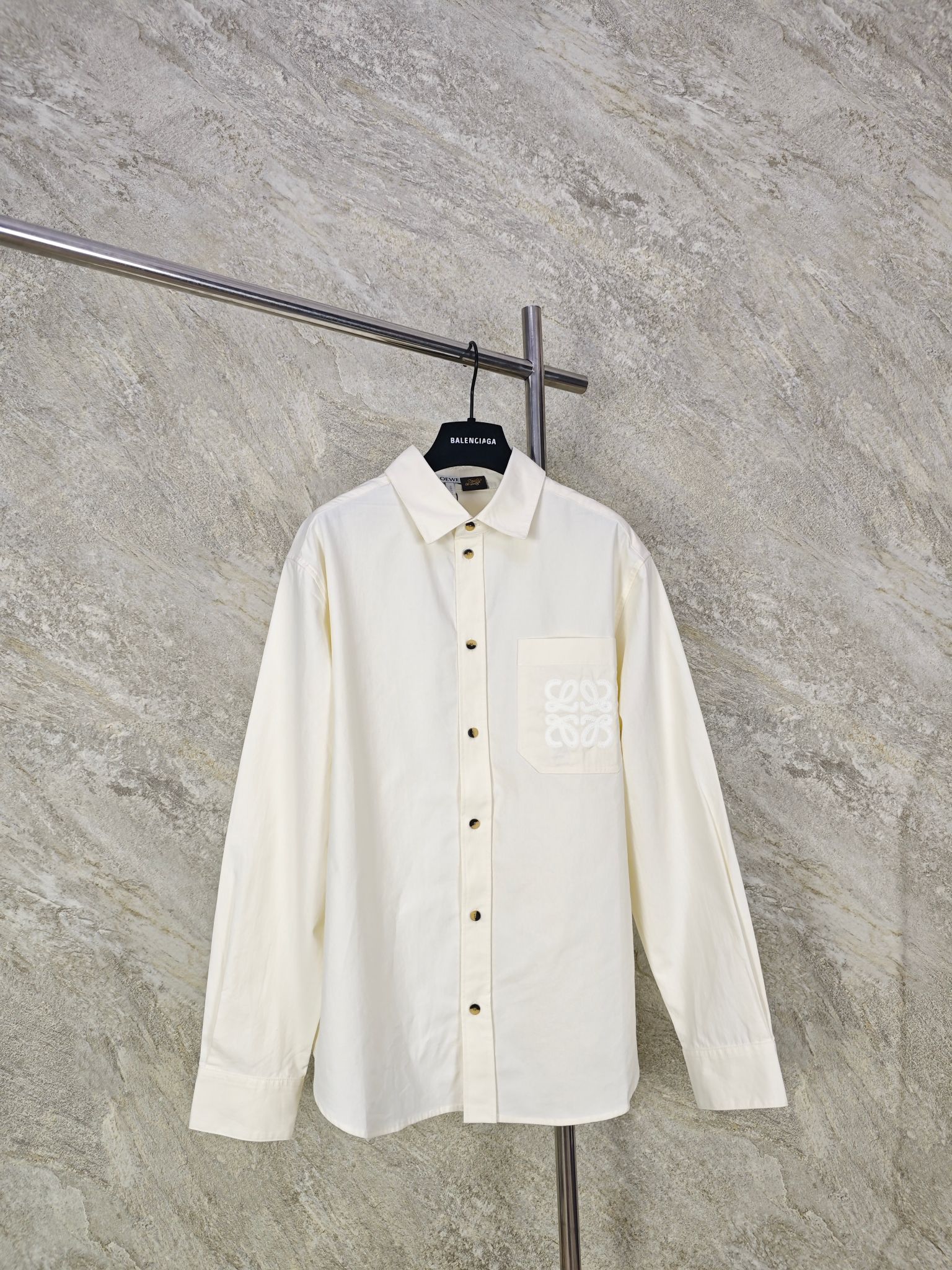 NO:885823,Top quality LOEWE patch pocket embroidered long sleeve shirt  Lyocell fabric is selected and extracted from natural wood pulp fibers. The fabric surface has a delicate and soft matte texture. It is soft and silky on the hand, has a superior drape feeling, and the upper body is neat and does not stick to the flesh. The hollow structure of the fiber can efficiently wick away moisture and quickly absorb sweat on the body surface. It also has a cooling feeling, saying goodbye to stuffy and sticky skin. After the pre-shrinking and shaping process, the shrinkage rate in washing is very low, and it is not easy to become hard and wrinkled.  Size:36384042,Loewe-clothing,loewe,loewe,shirts,19860909顶级品质 LOEWE贴袋刺绣长袖衬衫 甄选莱赛尔面料,取自天然木浆萃取纤维,布面自带细腻柔和哑光肌理,上手软糯丝滑,垂坠感优越,上身利落不贴肉；其纤维的中空结构能高效导湿排汗,快速吸收体表汗液,同时自带凉感,告别闷热黏身.经过预缩定型工艺处理之后,水洗缩水率极低,不易发硬起皱. Size:36384042,罗意威-服装,loewe,loewe,shirts,,Women's clothing