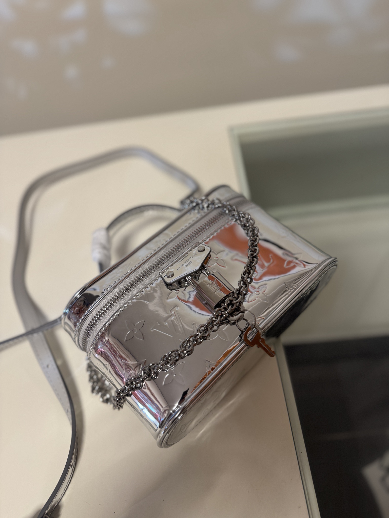 💰580VANITY CHAIN POUCH 手袋
M26097银色
本款 Vanity Chain Pouch 手袋出自 LV Ski 系列，向品牌传统化妆箱汲取灵感，以 Monogram Miroir 帆布诠释旅行精神。LV 字母铭纹挂锁、可拆卸肩带和链条彰显考究细节，恰宜构型可轻松容纳小型零钱包和太阳眼镜等日常所需。尺寸：11.5 x 6.5 x 19cm