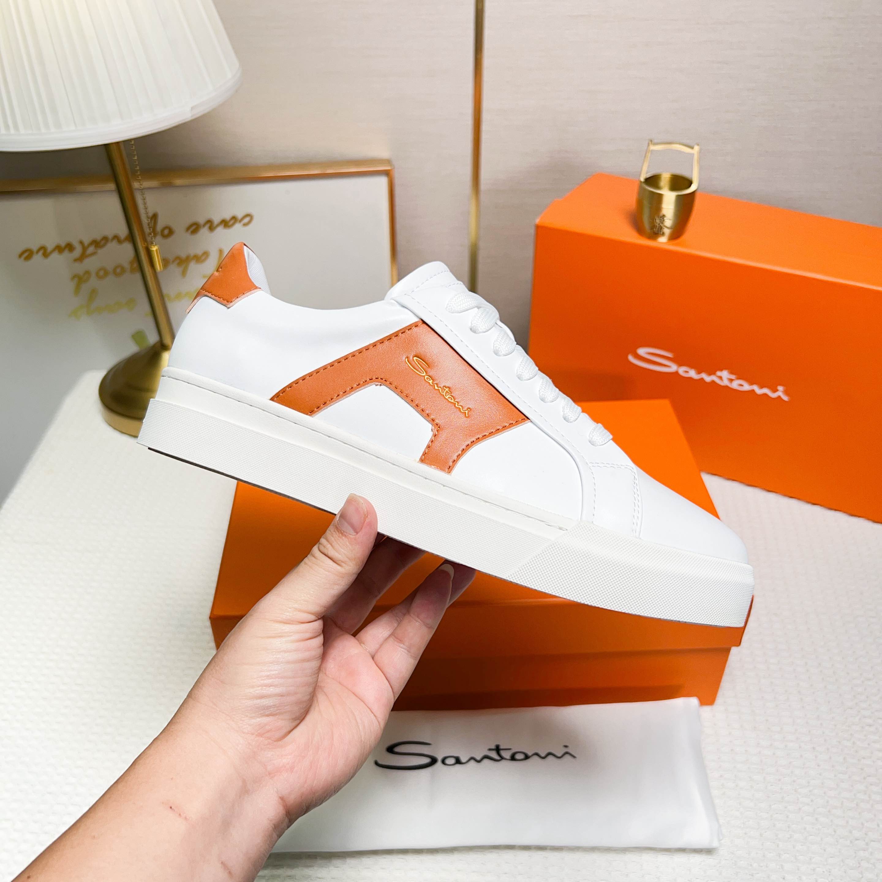 NO:272325,Santoni is a men's low-top sneaker made of leather, in white and orange, with exquisite and distinctive design details. Material and color The shoe is made of leather, the main color is white and orange, with bright and fashionable color. Design details The tongue and heel are decorated with leather brand logo, and the side design is designed with double buckles and inspiration for the shoe, which adds to the design sense of the shoe. The style and the shoes are worn are wide and round toe designed, and are comfortable to wear. The lace-up fixing method is used to facilitate adjustment of elasticity. The sole is constructed with rubber cup-shaped sole, which is wear-resistant and has good grip. The sole is molded with Santoni letters to highlight the brand's characteristics. Origin: The shoe is produced in Italy. This sneaker combines fashion and comfort, suitable for daily wear or special occasions.  38-44 codes (45 custom made), sneakers19860909Santoni(圣东尼) 这是一款男士低帮运动鞋,采用皮革材质,颜色 为白色和橙色,设计细节精致且富有特色. 材质与颜色该鞋采用皮革制作,主体颜色为 白色和橙色,配色鲜明且时尚. 设计细节鞋舌和鞋跟处饰有皮革品牌标识, 侧边设计有双扣环灵感的细节,增加了鞋子的设 计感. 版型与穿着鞋子为宽版型和圆头设计,穿着 舒适.采用系带式固定方式,方便调节松紧. 底部构造鞋底为橡胶杯型底,耐磨且具有良 好的抓地力.鞋底模印有Santoni字母,彰显品牌 特色. 产地该鞋产于意大利 这款运动鞋融合了时尚与舒适,适合日常穿着或 特殊场合搭配. 38-44码（45定做）,,sneakers,Men's shoes