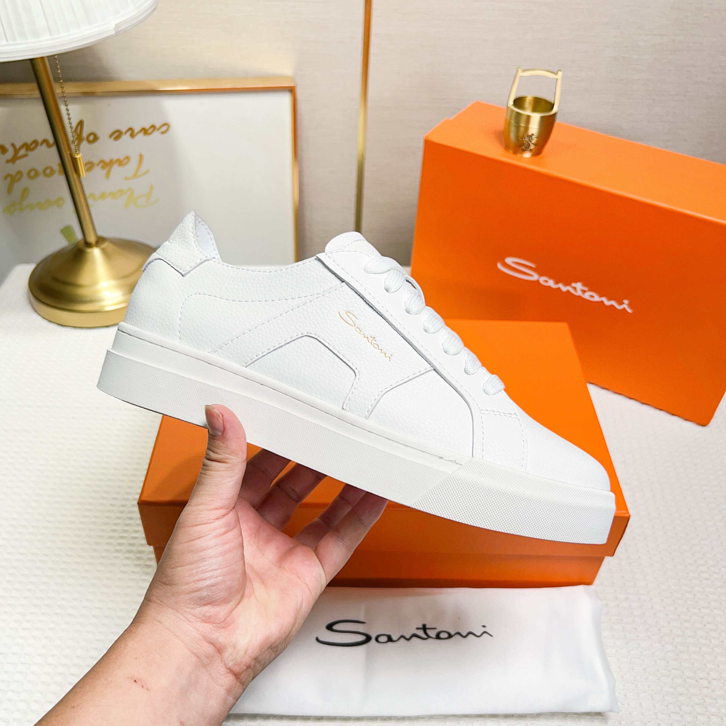 NO:272326,Santoni is a men's low-top sneaker made in Italy. The material and structure are made of lychee-shaped leather, unlined and deconstructed, giving a simple style. The color and details are white, with leather brand logo on the tongue and heel, and leather details inspired by double buckles on the sides to add a sense of fashion. The wear is lace-up design, which is convenient for adjusting tightness and ensuring a comfortable fit. The sole features rubber cup sole, which is wear-resistant and has strong grip, with Santoni letters printed on the bottom, highlighting the brand identity. This sneaker combines fashion and practicality, suitable for daily casual wear. Size 38-44 (customized for 45),, sneakers19860909Santoni(圣东尼) 这是一款男士低帮运动鞋,由意大利制造. 材质与构造采用荔枝纹皮革制作,未加内衬且解 构设计,呈现简约风格. 颜色与细节鞋身为白色,鞋舌和鞋跟处饰有 皮革品牌标识,侧边则以双扣环为灵感设计的皮 革细节,增添时尚感. 穿着方式采用系带设计,方便调整松紧度, 确保舒适贴合. 鞋底特色橡胶杯型鞋底,耐磨且抓地力强, 底部印有Santoni字母,彰显品牌身份. 这款运动鞋融合了时尚与实用,适合日常休闲穿 着. 38-44码（45定做）,,sneakers,Men's shoes