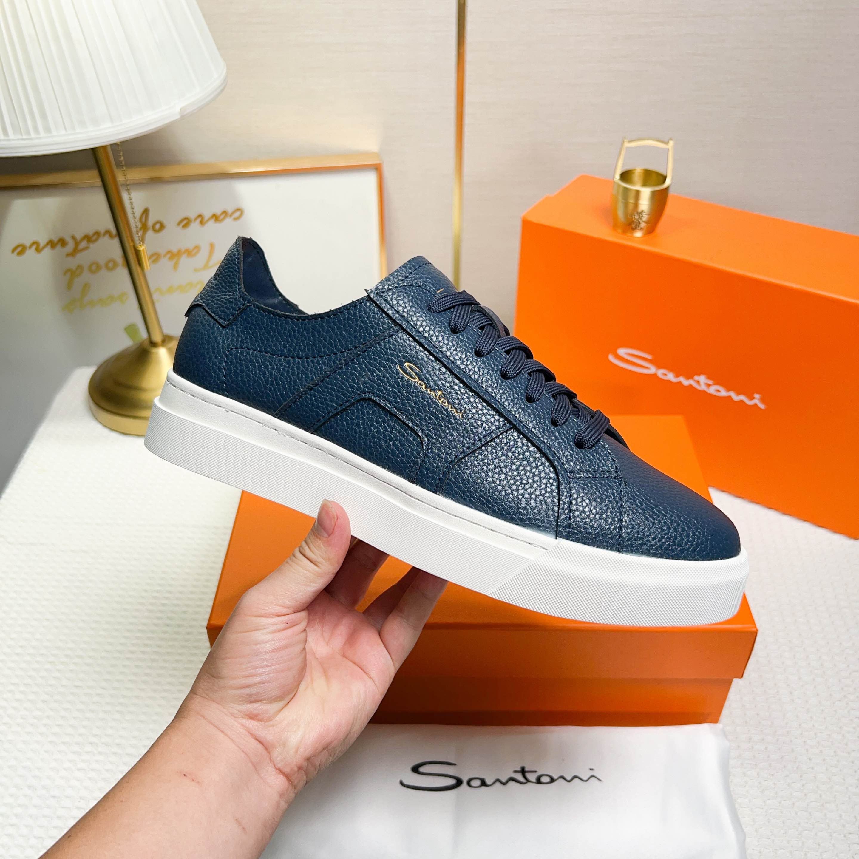 NO:272324,Santoni is a men's low-top sneaker made in Italy. The material and structure are made of lychee-shaped leather, unlined and deconstructed, giving a simple style. The color and details are blue, with leather brand logo on the tongue and heel, and the sides are inspired by double buckles to add a sense of fashion. The wear is lace-up design, which is convenient for adjusting the tightness and ensuring a comfortable fit. The sole features rubber cup sole, which is wear-resistant and has strong grip, and the Santoni letters are printed on the bottom, highlighting the brand identity. This sneaker combines fashion and practicality, suitable for daily casual wear. Size 38-44 (customized for 45),, sneakers19860909Santoni(圣东尼) 这是一款男士低帮运动鞋,由意大利制造. 材质与构造采用荔枝纹皮革制作,未加内衬且解 构设计,呈现简约风格. 颜色与细节鞋身为兰色,鞋舌和鞋跟处饰有 皮革品牌标识,侧边则以双扣环为灵感设计的皮 革细节,增添时尚感. 穿着方式采用系带设计,方便调整松紧度, 确保舒适贴合. 鞋底特色橡胶杯型鞋底,耐磨且抓地力强, 底部印有Santoni字母,彰显品牌身份. 这款运动鞋融合了时尚与实用,适合日常休闲穿 着. 38-44码（45定做）,,sneakers,Men's shoes