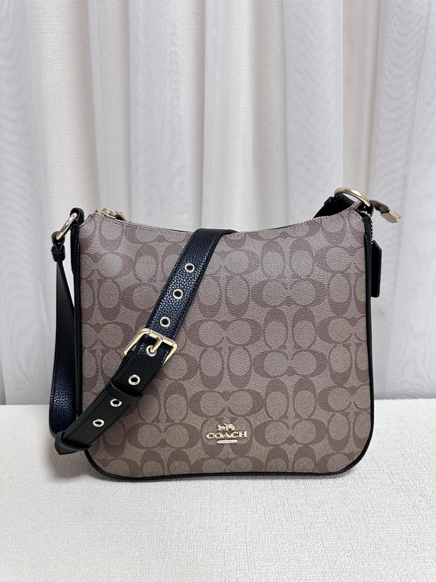 Coach C1649 Ellie crossbody bag features the iconic Coach C monogram pattern with a coated canvas and leather construction. It has an adjustable long strap, multiple interior pockets, top zip closure, exterior zip pocket, fabric lining, and a classic, trendy design. Available in khaki black color, dimensions 26*24*6. In stock now. image 1