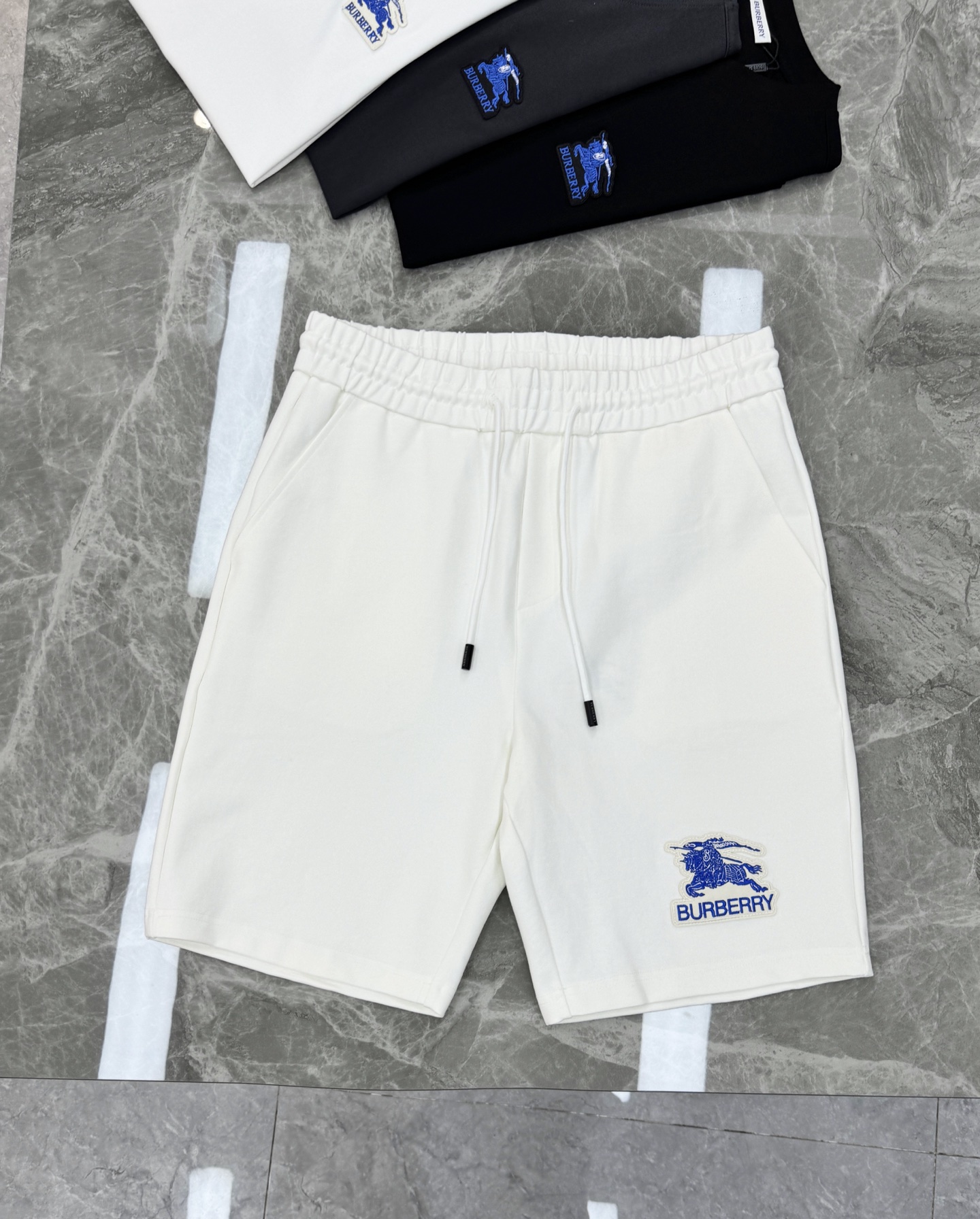 NO:833817,Burberry embroidered logo shorts. Can be matched as a set!  Made of selected nylon and cotton fabric, it is super comfortable to wear! Crisp and stylish!  The blue knight embroidery logo in the lower left corner and back pocket is very recognizable, full of British style. The elastic drawstring waistband is suitable for all kinds of body shapes, suitable for daily leisure or sports. The loose straight version is breathable and comfortable. Pair it with a T-shirt or sneakers in summer, and you can easily get a simple and fashionable look! Color: black. White. Size M-3XL (S and 4XL can be customized) Fitted version!  176/140 pounds recommended L,,burberry,burberry,sneakers,shorts,tees,t-shirt,19860909Burberry巴宝莉刺绣标志短裤.可成套搭配！采用精选锦棉面料,穿着超舒适!挺括有型！左下角及后口袋蓝色骑士刺绣标志超有辨识度,英伦风满满.松紧抽绳腰头,适合各种身材,日常休闲或运动都OK.宽松直筒版型,透气又自在,夏天搭配T恤或运动鞋,轻松get简约时尚 look!颜色黑色.白色.码数M-3XL（S和4XL可订做）合身版型！176/140斤建议L,,burberry,burberry,sneakers,shorts,tees，t-shirt,,Men's clothing