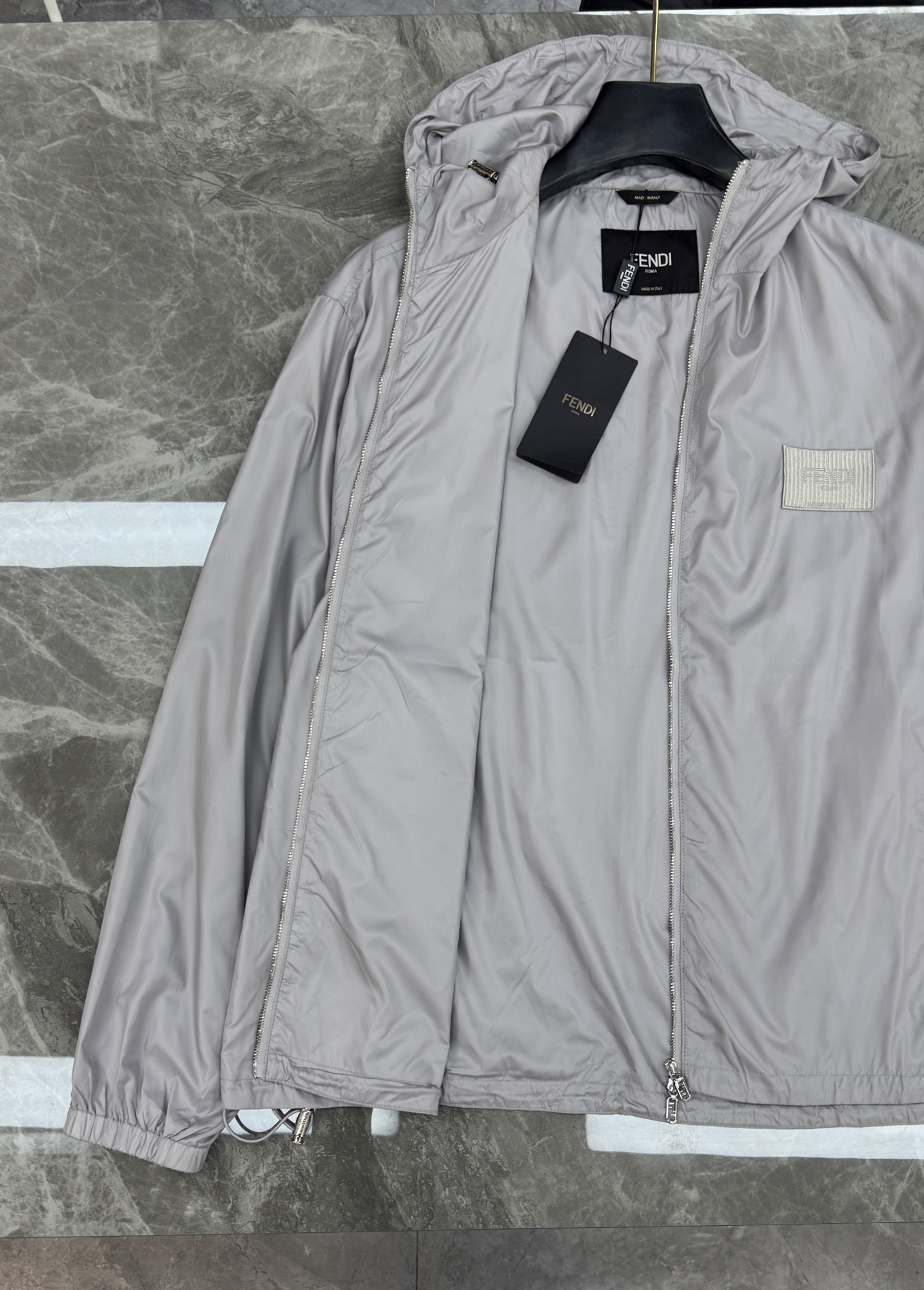 Fendi芬迪春款外套，男女同款！属于时尚服饰范畴。外套采用灰色材质，表面光滑有光泽，内衬带有Fendi