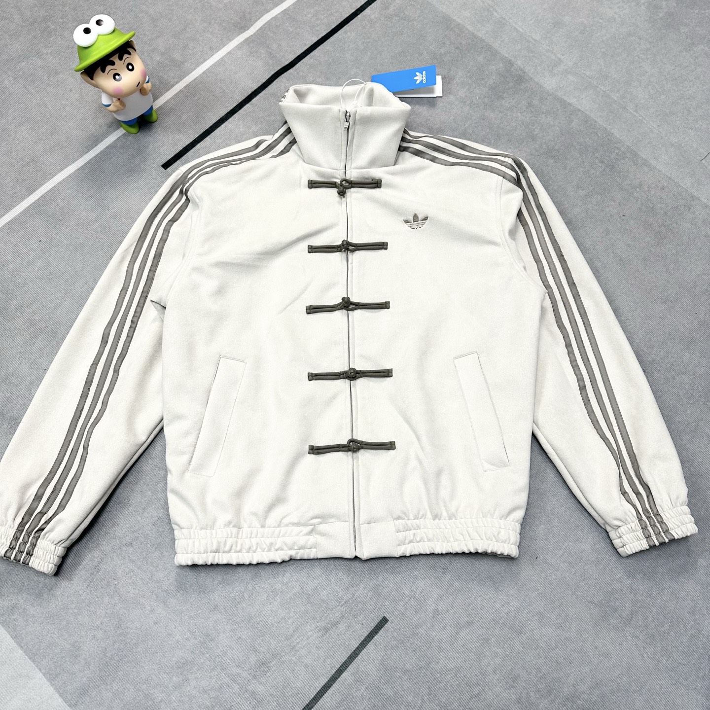 💰180【独家原版开发】
Adidas originals CTT 蛇年限定三叶草新中式盘扣麂皮立领唐装国风外套
时尚舒适百搭宽松条纹复古立领夹克 男女同款  
顶级复刻 全套辅料定制
AD三道杠男女同款唐装运动夹克，王安宇同款，新中式是阿迪的统治区，去年阿迪达斯三叶草唐装可谓是供不应求啊，今年CNY唐装又来啦！不同的是这次是麂皮面料，摸起来软软的，舒适且更具活力，打造复古中国风，上身慵懒时尚的潮流气息扑面而来！
2025蛇年限定新中式，四个颜色都超级好看，拍照都很出片，麂皮绒面料手感柔软舒适又亲肤，相对普通棉质布料更具质感，版型宽松有弹力，适应各类身材人群，上身效果宽松显瘦！
男女同款，大厂做工细节满分，定制原版带logo五金拉链，田岛绣花机精密刺绣，原版三标吊牌辅料齐全！
颜色:  藏青色 米白 柔和红
尺码:  S-XL
            衣长        胸围       肩宽         
S           68          120         56             
M          70          124         58          
L           72           128         60
XL         74           132         62