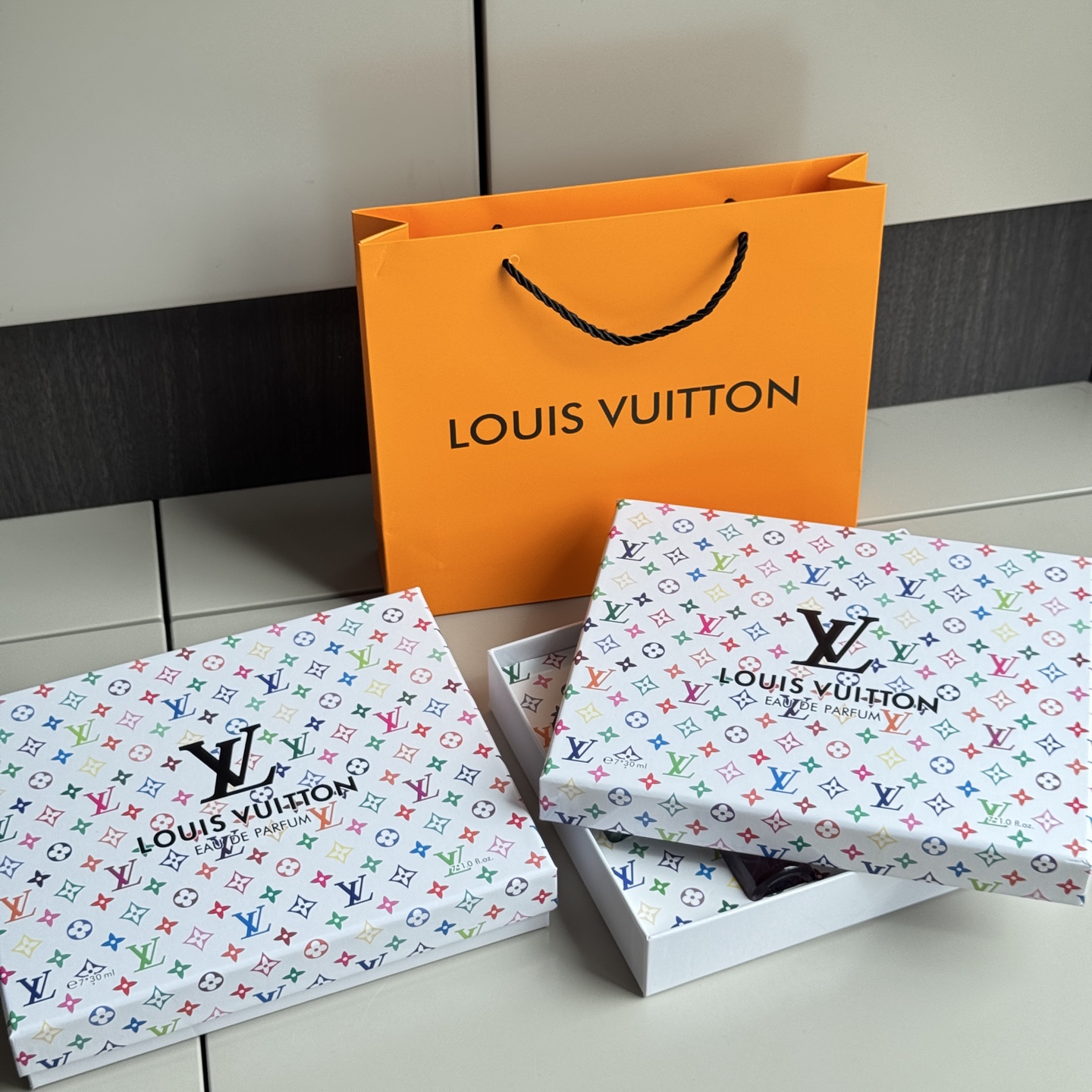 NO:879281,I have to praise the packaging of this set of LV perfume gift boxes. The surface of the gift box is full of colorful presbyopia patterns, and the classic elements are re-matched to make it simple and fashionable. The concave and convex brand logo enhances the sense of sophistication. The inside of the flip-top gift box is neat and can store 7 bottles of perfume stably. All the fragrance types are marked on the back of the box, making it easy to choose the fragrance at a glance.  Plus the original orange handbag, the complete set. It brings a high-end atmosphere as a gift, and it is also a beautiful ornament for personal use at home., perfume, louis vuitton19860909不得不夸这套LV香水礼盒的包装. 礼盒表面是彩色满印老花图案,经典元素重新配色,简约又时髦,凹凸的品牌logo提升精致感. 翻盖礼盒内里规整,可以稳稳收纳7瓶香水,盒背标注全部香型,挑选香气一目了然. 外加原版橙色手提袋,整套完整成套.送人自带高级氛围感,自用摆放在家中,也是一件好看的摆件.,香水,louis vuitton,accessory