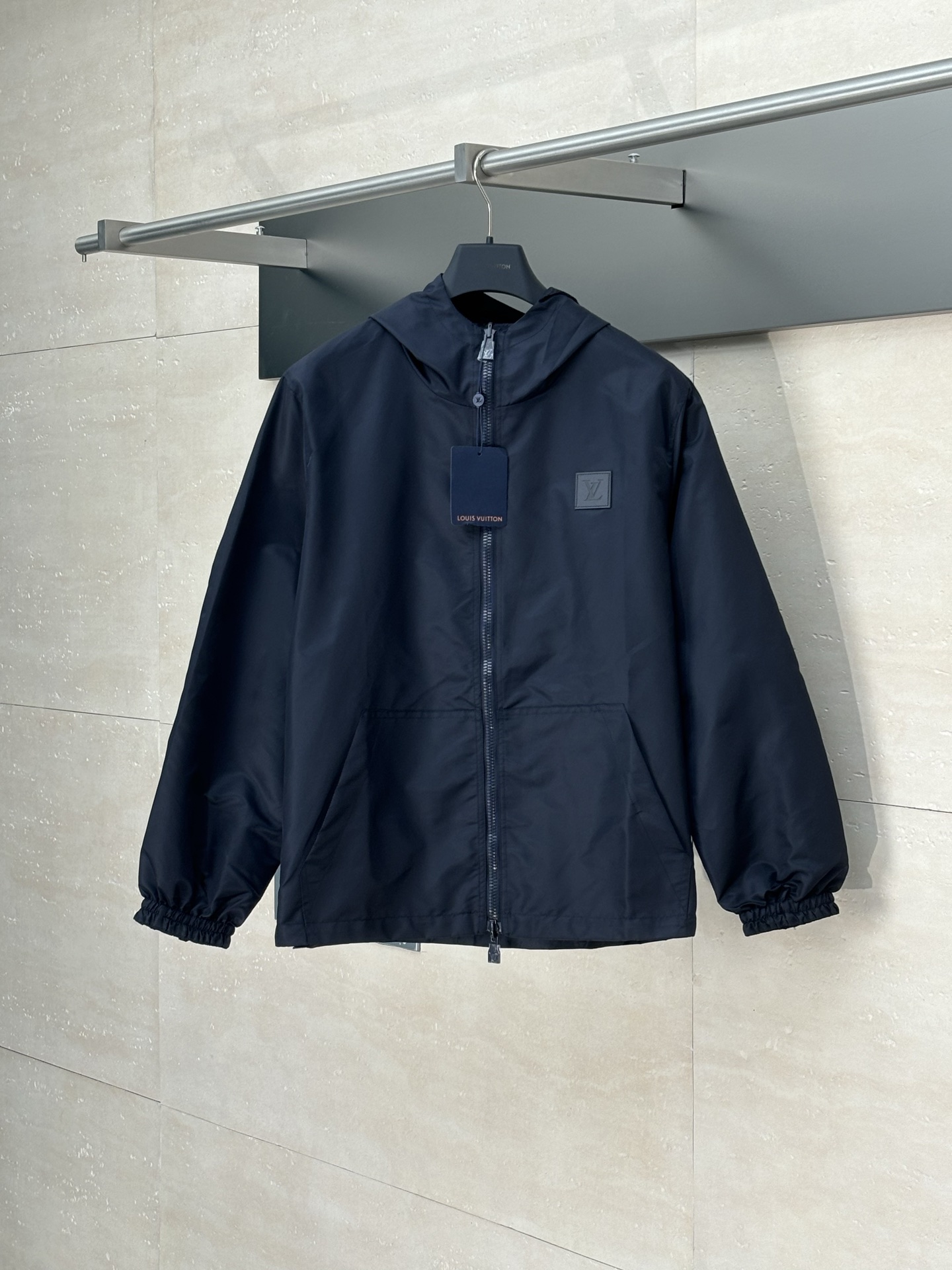 NO:876437,1V*/Louis 25Fw new double-sided old flower jacquard windproof jacket (navy blue)  The solid color fabric is made of nylon encrypted matt twill fabric, and the jacquard fabric on the other side is made of 50D nylon yarn-dyed jacquard fabric. The solid color front panel is laser-burned, hand-made of white copper, with a triangular pin with a logo surface sprayed with glossy paint. The front pocket uses a hardware keychain to hang a folding clothes tag, and the jacquard letter front chest placket is made of single-piece handmade  Restore flower cutting, all cut pieces are numbered, and the pockets are also cut with restored flower numbers. The fabric is relatively light and silky, and it takes time to cut accurately. The front and center are equipped with a double-circulation slider 5# orbital zipper, and the hem is worn with a spiral elastic rope with a ring anti-slip buckle, a square pig nose buckle with a logo, and all holes are punched with hardware with a logo on the fabric color cornrows.  SizeS/M/L/XL,,louis vuitton,jackets & coats,keychain,198609091V*/路易 25Fw新款双面老花提花防风外套（藏青） 净色面料采用尼龙加密消光斜纹布,另一面提花面料采用50D尼龙色织提花布,净色前幅定位激光烧花,手工穿白铜材质,带logo表面喷亮面漆三角形别针,前幅插袋处采用五金件钥匙扣挂折叠挂衣牌,提花字母面前胸门襟采用单件流纯手工还原花裁剪,裁片全部打编号,插袋也是还原花编号剪裁,面料比较轻薄丝滑,要裁剪的精准极耗费时间,前中搭配双循环拉头5#轨道牙拉链,下摆跟穿螺旋纹弹力绳搭配圆环防滑扣,方形带logo猪鼻扣,全部开孔打五金带logo对布色鸡眼 SizeS/M/L/XL,,louis vuitton,jackets & coats,keychain,,Men's clothing