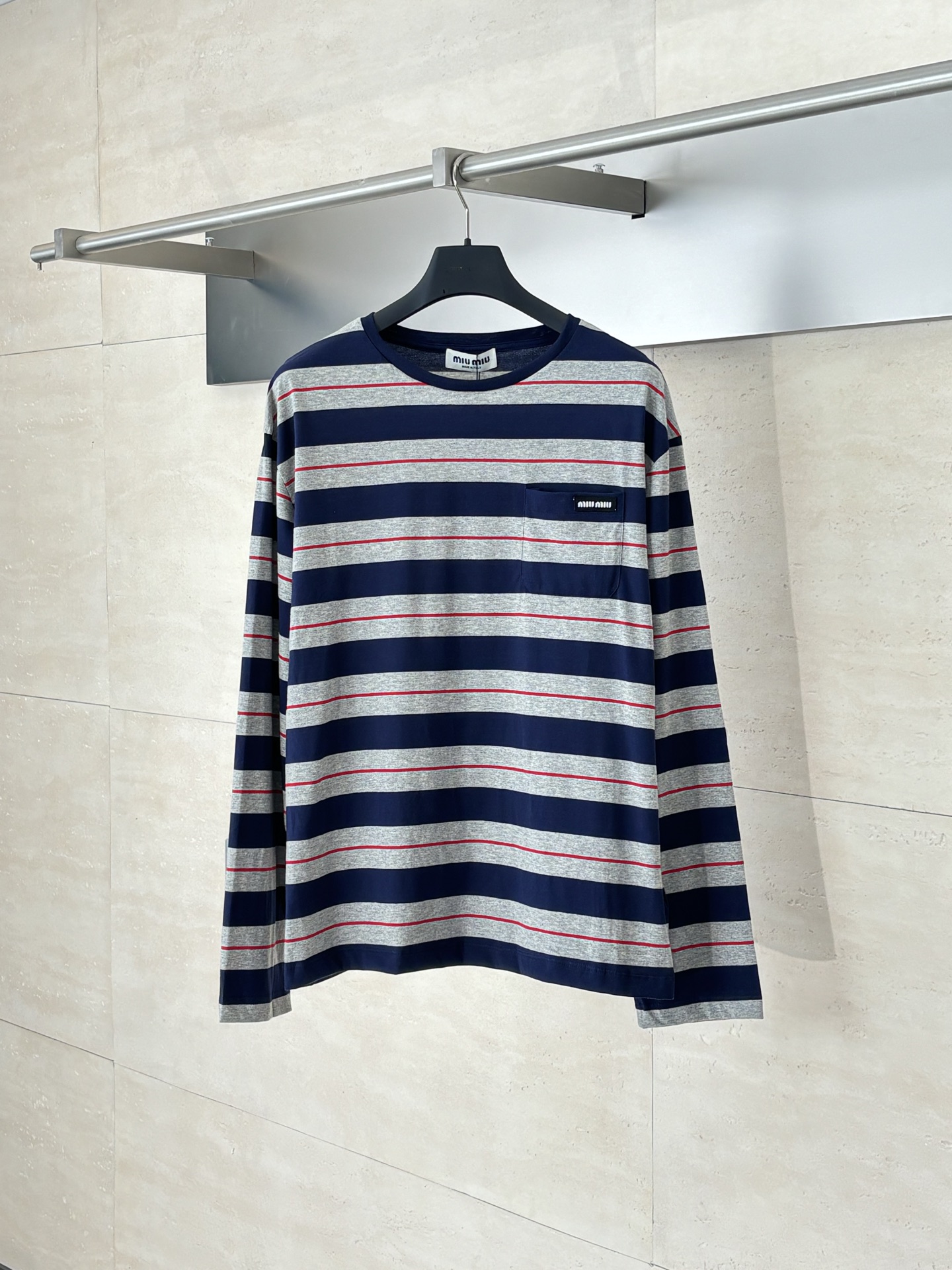 NO:530356,MiuMi*/MuMi*/MuMi 25SS gray-blue striped long sleeves 60-strand double-strand yarns are made of 60S 200G high-subscription combed cotton. The double-strand twisting process improves the strength of the yarn, making the fabric more delicate, crisp, wrinkle-resistant, while maintaining a soft and skin-friendly feel. The classic Jersey knitted structure provides good elasticity and drape, suitable for slim-fitting and texture on the front and back sides, ensuring accurate strip alignment. From the yarn ratio, density to gram weight, they are customized according to the original requirements to ensure color saturation and stripe clarity. When cutting, the fabric strips must be strictly aligned at the front and rear pieces, armholes, side seams and other joints. The shoulder lines and sleeves are spliced ​​obliquely to reduce distortion; due to the extremely high requirements for grids, the fabric utilization rate may be as low as 60 (ordinary garments can reach 85), and the cost has increased significantly.  SizeS/M/L, miumiu,alexander wang19860909MiuMi*/缪缪 25SS 灰蓝条纹长袖 定织60支双股纱线采用60S 200G高支数精梳棉,双股加捻工艺提升纱线强度,使面料更细腻、挺括、抗皱,同时保持柔软亲肤感.平纹针织结构经典的Jersey针织提供良好的弹性和垂感,适合修身剪裁,且正反面纹理一致,确保条纹对位精准.从纱线配比、密度到克重均按原版要求定制,确保色彩饱和度和条纹清晰度. 裁片对位在裁剪时,需将面料条纹在前后片、袖窿、侧缝等接缝处严格对齐.肩线、袖笼采用斜裁拼接以减少扭曲；因对格要求极高,面料利用率可能低至60（普通成衣可达85）,成本大幅上升.  SizeS/M/L,,miumiu,alexander wang,Men's clothing