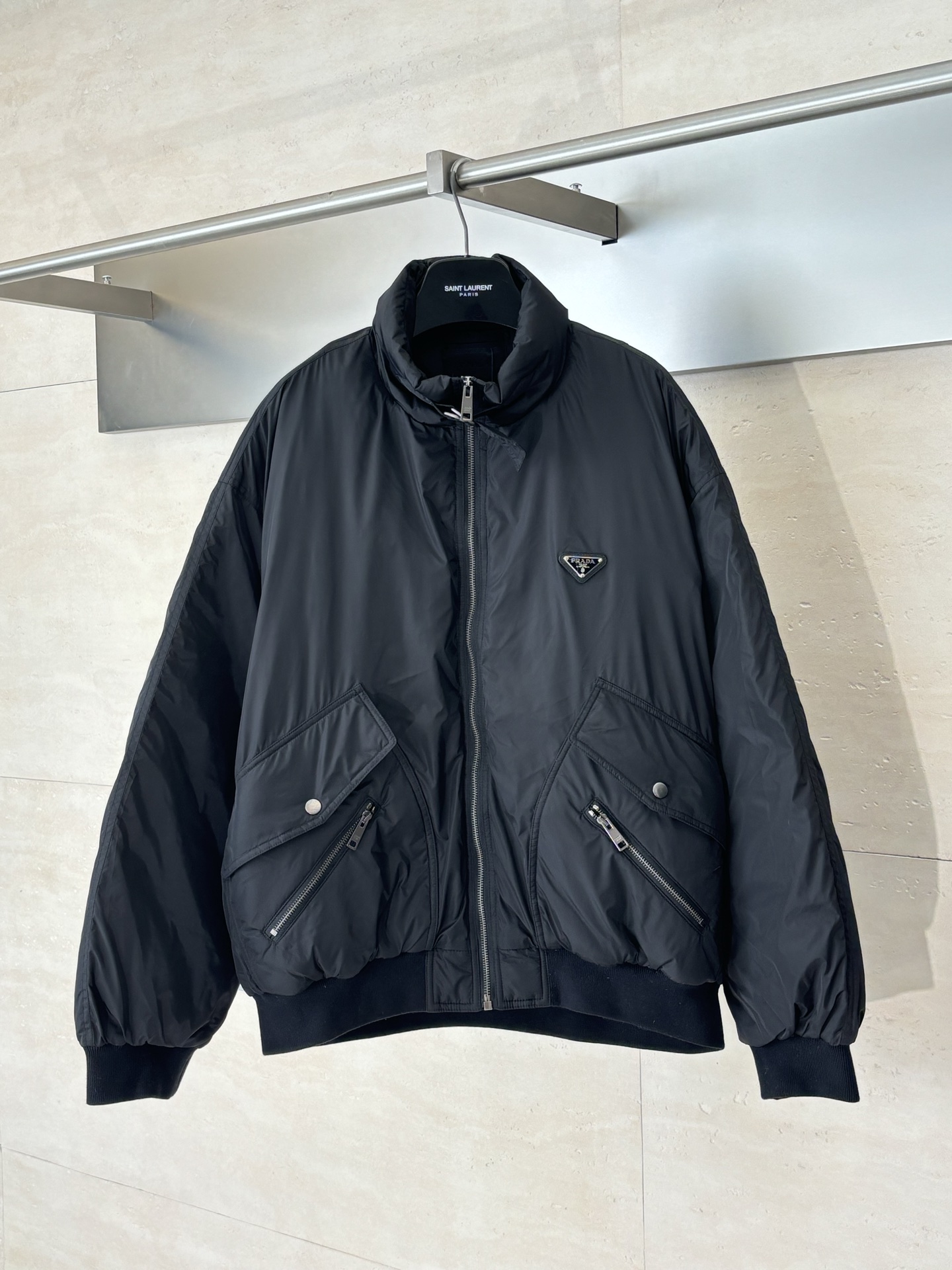 NO:539828,Prad*/Prada 25FW Heavy Industry Nylon Zipper Down Jacket Filling 90 White Duck Down Complexity is reflected in the strict control of 'purity' and 'quality'. '90 White Duck Down' means that the content of down in the fill is as high as 80, and the remaining 10 are small feathers. The down is a flower-shaped structure in the down, responsible for catching air and providing excellent warmth. Its content is the gold standard for measuring down quality. High-spec white Duck Down needs to go through strict sorting, cleaning, disinfection and drying processes to ensure that it is light, odorless, high fluffy and rich in oil, so as to provide excellent warmth while greatly reducing the overall weight of the clothing. The ribbed on the neckline, cuffs and hem is not ordinary elastic fabric, but 'customized flat thread'  .This process is woven in a specific program on advanced knitting machines. The complexity lies in the precision structure. The flat ribs have a tighter structure and stronger elastic recovery. It can effectively prevent cold air from intrusion and avoid loosening due to long-term use. SizeS/M/L,,prada,prada,down jacket,gold,alexander wang19860909Prad*/普拉达 25FW 重工尼龙拉链羽绒服 填充物90白鸭绒 复杂性体现在“纯度”与“品质”的严格控制.“90白鸭绒”意味着填充物中绒子的含量高达80,其余10为小羽毛.绒子是羽绒中呈朵状的结构,负责捕捉空气、提供绝佳保暖性,其含量是衡量羽绒品质的黄金标准. 高规格的白鸭绒需经过严格的分拣、清洗、消毒和干燥流程,确保其轻盈、无味、高蓬松度且富含油脂,从而在提供卓越保暖效果的同时,极大程度地减轻了服装的整体重量. 领口、袖口及下摆的罗纹并非普通弹性面料,而是 “定制扁机螺纹” .这种工艺在高级针织机上以特定程序织造,其复杂性在于结构精密,扁机罗纹的结构更紧密、弹性恢复力更强,能有效防止冷风侵入,同时避免因长期使用而变得松弛. SizeS/M/L,,prada,prada,down jacket,gold,alexander wang,Men's clothing
