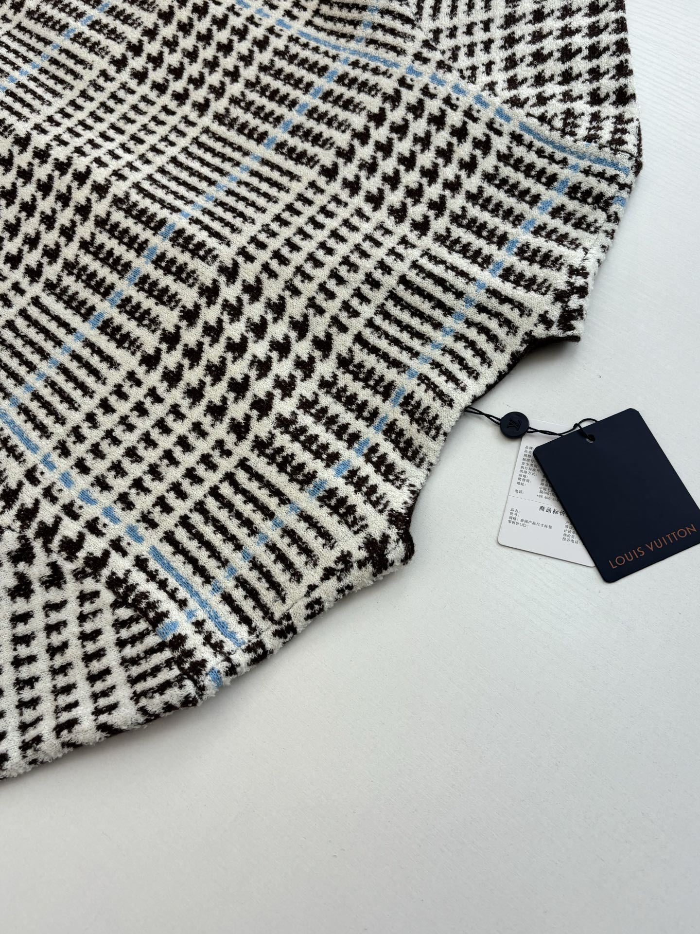 P265
1V/路易 SS26 早春新款 字母嵌花千鸟格针织提花开衫

本款开衫采用全幅提花工艺织造主体图案，以69%绵羊毛混纺31%锦纶的纱线，将千鸟格纹与淡蓝色线条肌理交织呈现，同时通过嵌花工艺在衣身融入品牌标识元素，图案边缘衔接细腻无断层。领口、袖口及下摆选用100%绵羊毛罗纹面料，采用双针锁边工艺收边，兼具弹性与定型效果。前襟配备天然质感纽扣，侧缝口袋采用隐形车线工艺，与衣身提花纹理自然融合。整体版型通过立体剪裁定型，肩部采用无痕缝合工艺，确保穿着贴合度与舒适度，全件由意大利工坊手工细节收尾，呈现高质感针织单品的工艺精度。整体走线平直细腻，面料舒适柔软，颜色一致无色差 能与同款搭配营造时尚造型，驾驭各种场合，定制辅料，三标齐全，男女同款！

Size：S/M/L/XL