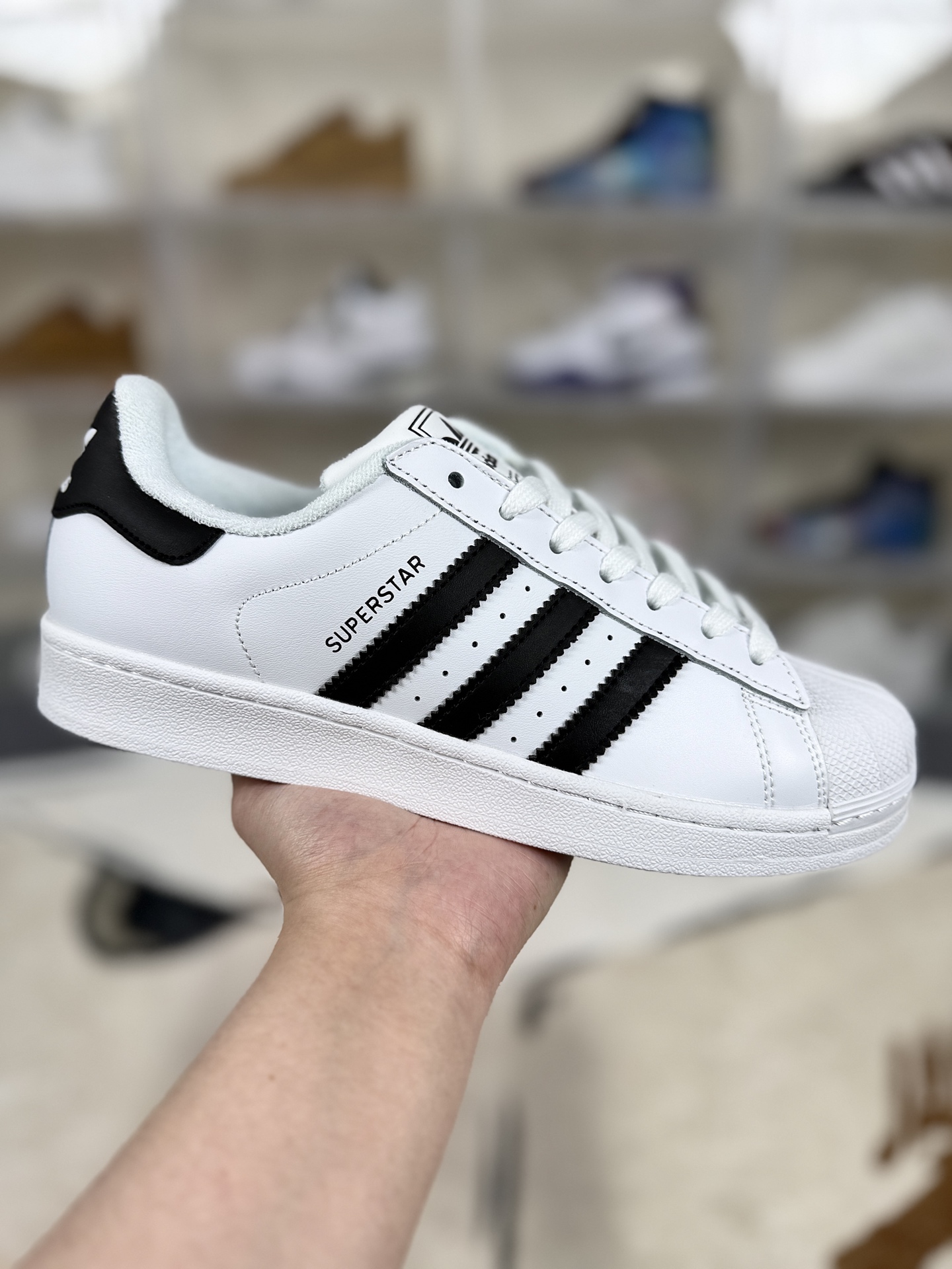 本地💰150   
▪️D版纯原
adidas originals Superstar 2 百搭舒适 低帮 板鞋 男女同款 白黑
▪️尺码：35.5-45（35⅔ 36 36⅔ 37⅓ 38 38⅔ 39⅓ 40 40⅔ 41⅓ 42 42⅔ 43⅓ 44 45⅓）
▪️货号：JH9976
▪️Superstar系列以贝壳头设计著称，这一标志性元素使其在众多鞋款中脱颖而出。贝壳头不仅具有防撞和保护脚尖的作用，还成为了时尚界的经典符号。作为阿迪达斯经典系列的一部分，Superstar鞋侧常常饰有三叶草标志，彰显品牌身份与品质保证。鞋面采用优质皮革，质感高级且耐磨耐穿。柔软橡胶底则提供了良好的缓震效果和抓地力。Superstar板鞋以其舒适的穿着体验而著称。柔软橡胶底和合理的内部空间设计，使得长时间穿着也不会感到疲劳。简约复古的鞋型搭配贝壳头设计，使得Superstar成为一款百搭鞋款。无论是搭配牛仔裤、休闲裤还是裙子，都能轻松驾驭各种风格。采用优质材质和精湛工艺打造，Superstar板鞋具有出色的耐用性和耐磨性，能够陪伴消费者度过漫长的时光。自诞生以来，Superstar逐渐成为街头潮流文化的代表之一。众多潮人、明星和设计师都钟爱这款鞋款，纷纷将其纳入自己的穿搭中。