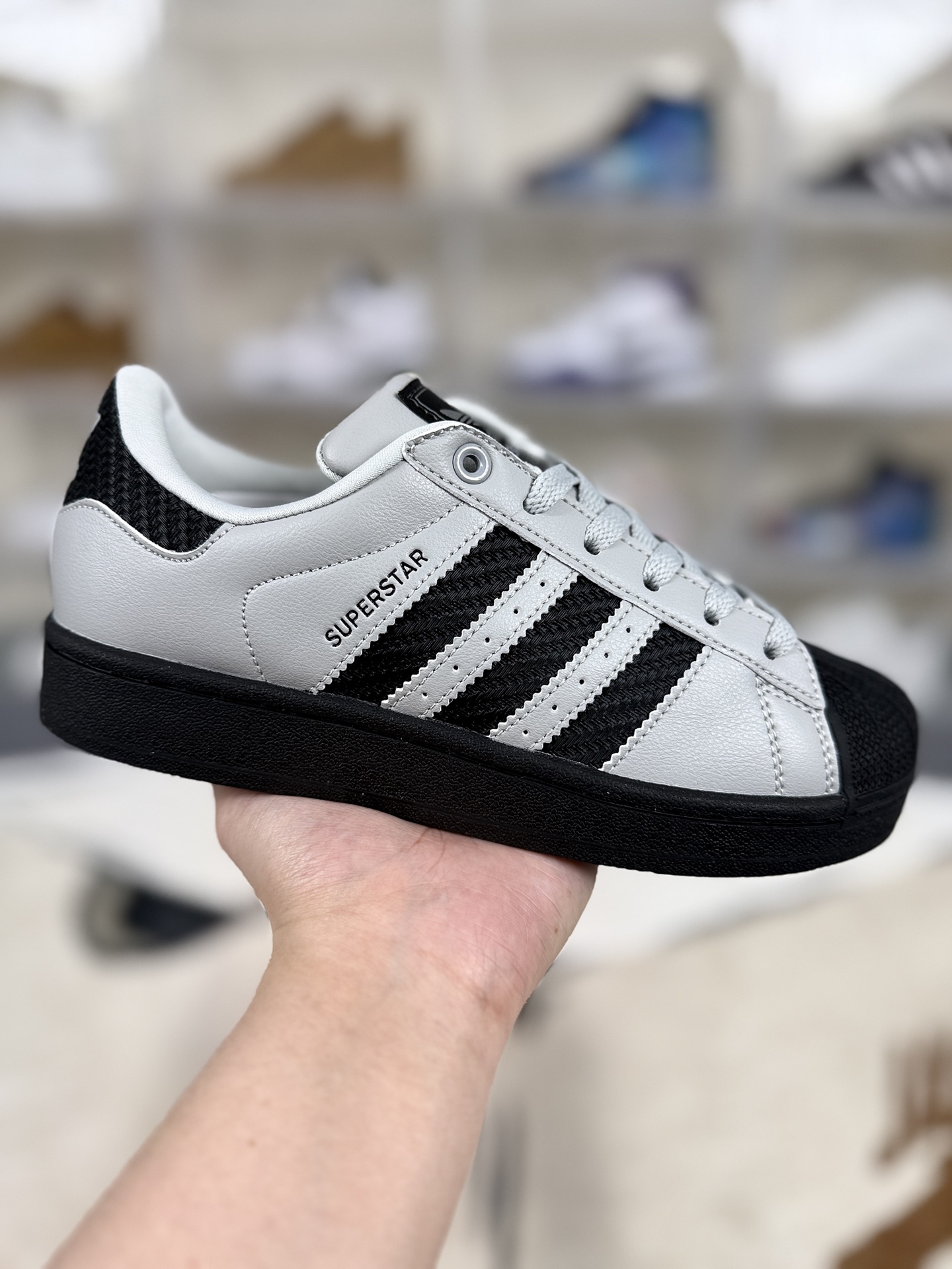 本地💰150   
▪️D版纯原
adidas originals Superstar 2 百搭舒适 低帮 板鞋 男女同款 灰黑
▪️尺码：35.5-45（35⅔ 36 36⅔ 37⅓ 38 38⅔ 39⅓ 40 40⅔ 41⅓ 42 42⅔ 43⅓ 44 45⅓）
▪️货号：JQ3183
▪️Superstar系列以贝壳头设计著称，这一标志性元素使其在众多鞋款中脱颖而出。贝壳头不仅具有防撞和保护脚尖的作用，还成为了时尚界的经典符号。作为阿迪达斯经典系列的一部分，Superstar鞋侧常常饰有三叶草标志，彰显品牌身份与品质保证。鞋面采用优质皮革，质感高级且耐磨耐穿。柔软橡胶底则提供了良好的缓震效果和抓地力。Superstar板鞋以其舒适的穿着体验而著称。柔软橡胶底和合理的内部空间设计，使得长时间穿着也不会感到疲劳。简约复古的鞋型搭配贝壳头设计，使得Superstar成为一款百搭鞋款。无论是搭配牛仔裤、休闲裤还是裙子，都能轻松驾驭各种风格。采用优质材质和精湛工艺打造，Superstar板鞋具有出色的耐用性和耐磨性，能够陪伴消费者度过漫长的时光。自诞生以来，Superstar逐渐成为街头潮流文化的代表之一。众多潮人、明星和设计师都钟爱这款鞋款，纷纷将其纳入自己的穿搭中。