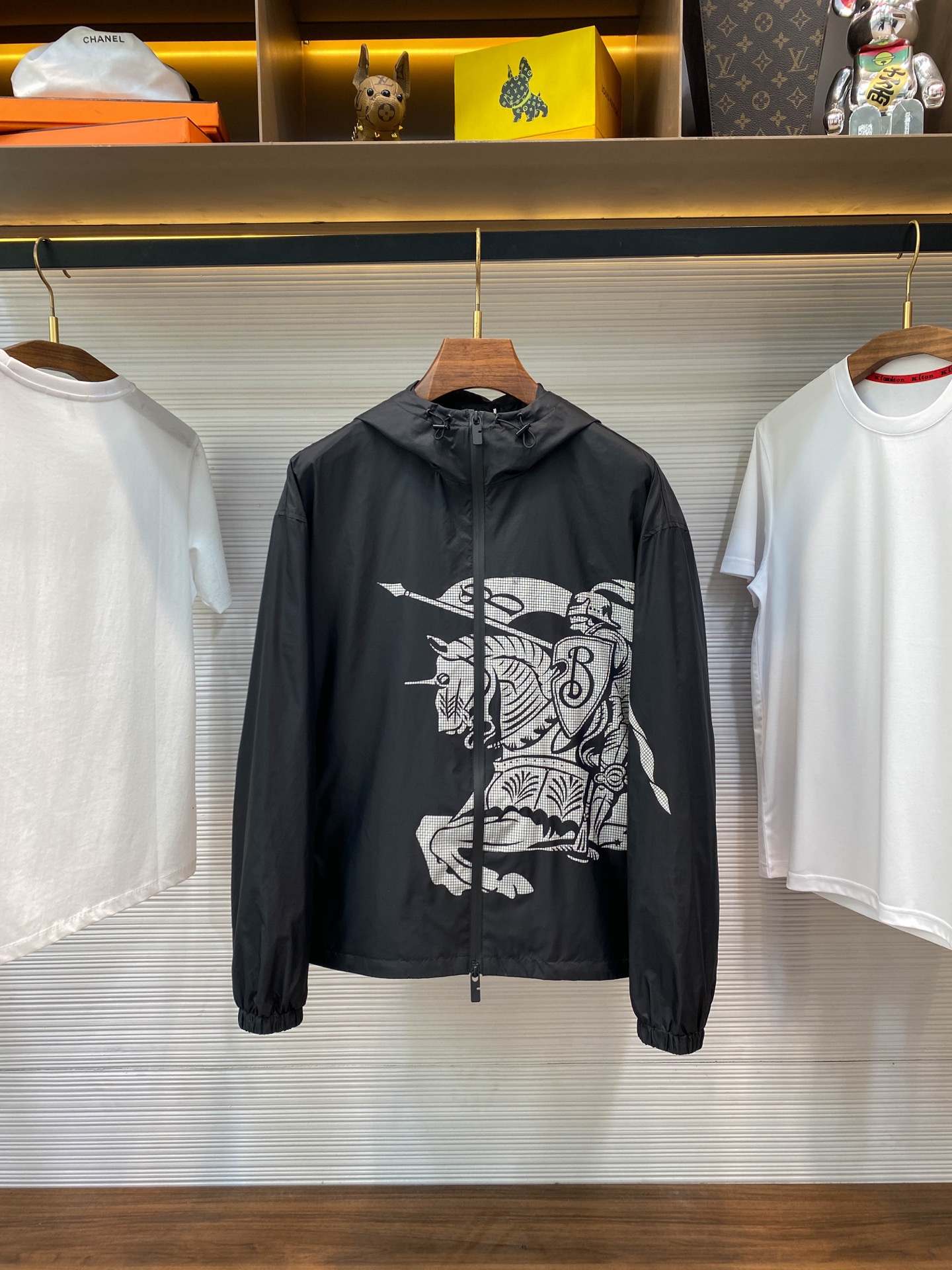 NO:573526,Burber Equestrian Rider Logo Jacket Jacket The fabric is made of high-quality nylon fabric, which is lightweight, LL1670350 wear-resistant, windproof and waterproof, and is very suitable for making casual jackets. In the fabric processing, special waterproof coating treatment technology is used to enhance its waterproof performance. Cutting and sewing According to the design drawings, the fabric is cut into the required shape and size. Advanced sewing equipment and technology are used to sew the fabrics together to form the overall structure of the jacket.  During the sewing process, special attention is paid to detail processing, such as the sewing of zippers, pockets, cuffs, etc., to ensure their firmness and beauty. The logo pattern needs to be restored very accurately. Logo and printing processing The Equ19860909Burber马术骑士徽标 冲锋衣夹克外套 面料由高品质的尼龙面料,具有轻盈、LL1670350耐磨、防风防水等特性,非常适合制作休闲夹克. 在面料处理上,采用特殊的防水涂层处理技术,以增强其防水性能. 裁剪与缝制 根据设计图纸,将面料裁剪成所需形状和尺寸. 使用先进的缝制设备和技术,将面料缝制在一起,形成夹克的整体结构. 在缝制过程中,特别注意细节处理,如拉链、口袋、袖口等部位的缝制,确保其牢固度和美观度. 需要非常精准的还原徽标图案 徽标与印花处理 通过胶浆印花将马术骑士徽标（EKD）和B字型拉链头装饰在夹克上,彰显品牌特色. 印花处理采用环保、耐洗的颜料,确保印花持久、鲜艳. 抽绳式连帽与衣摆设计,可根据天气变化调整松紧度,提供更好的防护效果. 后整与检验 对缝制好的夹克进行后整处理,如熨烫、去线头等,使其更加平整、美观. 进行严格的质量检验 SIZE:S-XL,,burberry,jackets & coats,jackets & coats,hats,alexander wang,Men's clothing