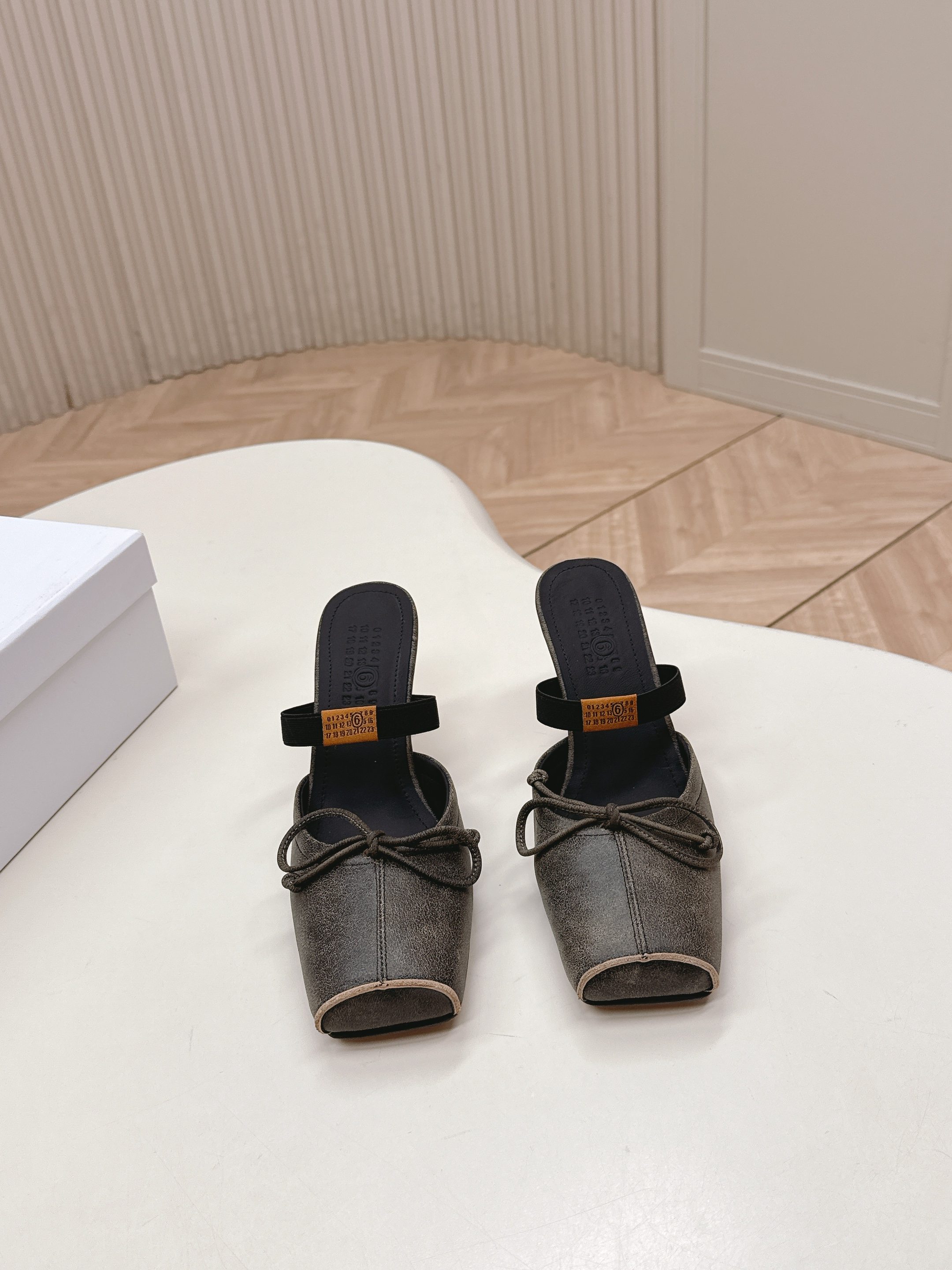 NO:669903,Maison Margiel 26 spring and summer retro square toe elastic band ballet shoes, high heels and sandals series adopt the brand's iconic sculptural silhouette that fits the shape of the foot. The upper is soft and smooth, taking into account both fit and design. The square toe + ballet elements are combined with the classic square toe design to create a modern feel. It is matched with the bow decoration on the upper to reconstruct the elegant outline of the ballet shoes. At the same time, it is made into a mules-back style, which is both casual and refined.  There is the iconic white single-thread stitching on the heel, and the elastic band of the shoe body has the MM6 digital logo, which is the key to brand recognition. The empty mule slide structure simplifies the way of putting on and taking off, combining the softness of ballet shoes with the casualness of mule shoes. The upper is retro burst cowhide, the lining is silk sheepskin, the outsole is genuine leather, and the high-heeled model is 8cm size: 35-41 sizes (customized sizes 40 and 41 are not returnable), half-slip slippers, masion  margiela,sandals,high heels,slippers,cowhide,sheepskin,Leather soles19860909出 Maison Margiel 26春夏款复古方头弹力带芭蕾鞋高跟鞋凉鞋系列 采用品牌标志性的贴合脚型的雕塑感轮廓,鞋面柔软且线条流畅,兼顾贴合度与设计感.方头+芭蕾元素融合经典方头设计打造现代感,搭配鞋面蝴蝶结装饰,重构芭蕾鞋的优雅轮廓,同时做穆勒拖的后空款式,兼具休闲与精致. 鞋后跟处有标志性的白色单线缝线,鞋身弹性带带有MM6数字标识,是品牌辨识度的关键.后空的穆勒拖结构,简化穿脱方式,将芭蕾鞋的柔美与穆勒鞋的随性结合. 鞋面复古爆裂牛皮 内里丝绸羊皮里 大底真皮大底 高跟款8cm size :35-41码（40、41码定制不退换）,半拖拖鞋,masion margiela,sandals,high heels,slippers,cowhide,sheepskin,Leather soles,Women's Shoes