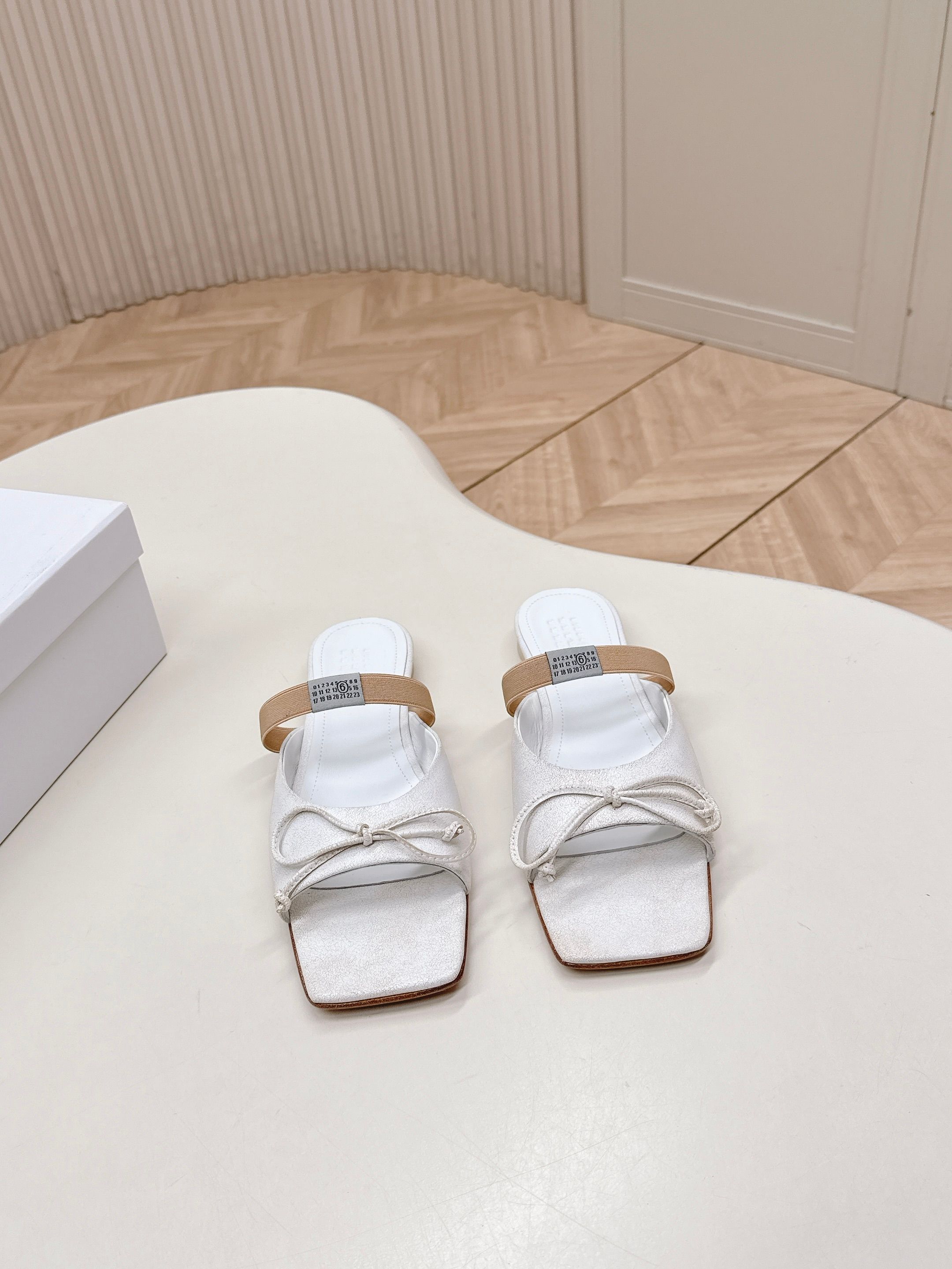 NO:669905,Maison Margiel 26 spring and summer retro square toe elastic band ballet shoes, high heels and sandals series adopt the brand's iconic sculptural silhouette that fits the shape of the foot. The upper is soft and smooth, taking into account both fit and design. The square toe + ballet elements are combined with the classic square toe design to create a modern feel. It is matched with the bow decoration on the upper to reconstruct the elegant outline of the ballet shoes. At the same time, it is made into a mules-back style, which is both casual and refined.  There is the iconic white single-thread stitching on the heel, and the elastic band of the shoe body has the MM6 digital logo, which is the key to brand recognition. The empty mule slip structure simplifies the way to put on and take off, combining the softness of ballet shoes with the casualness of mule shoes. The upper is retro burst cowhide, the lining is silk sheepskin, and the outsole is genuine leather. Size: 35-41 (customized sizes 40 and 41 are not returnable), half-slip slippers, masion  margiela,sandals,high heels,slippers,cowhide,sheepskin,Leather soles19860909出 Maison Margiel 26春夏款复古方头弹力带芭蕾鞋高跟鞋凉鞋系列 采用品牌标志性的贴合脚型的雕塑感轮廓,鞋面柔软且线条流畅,兼顾贴合度与设计感.方头+芭蕾元素融合经典方头设计打造现代感,搭配鞋面蝴蝶结装饰,重构芭蕾鞋的优雅轮廓,同时做穆勒拖的后空款式,兼具休闲与精致. 鞋后跟处有标志性的白色单线缝线,鞋身弹性带带有MM6数字标识,是品牌辨识度的关键.后空的穆勒拖结构,简化穿脱方式,将芭蕾鞋的柔美与穆勒鞋的随性结合. 鞋面复古爆裂牛皮 内里丝绸羊皮里 大底真皮大底 size :35-41码（40、41码定制不退换）,半拖拖鞋,masion margiela,sandals,high heels,slippers,cowhide,sheepskin,Leather soles,Women's Shoes