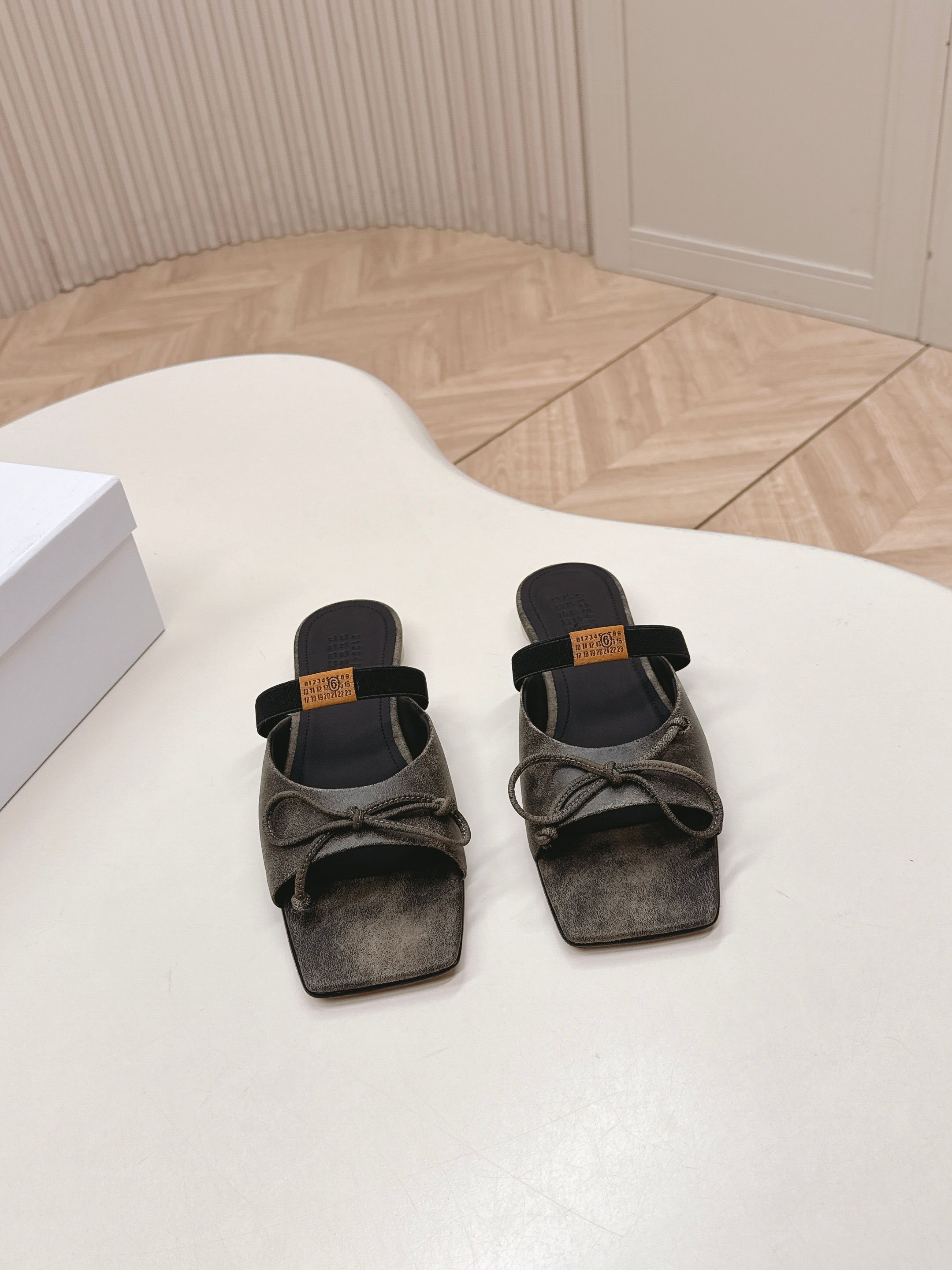 NO:669907,Maison Margiel 26 spring and summer retro square toe elastic band ballet shoes, high heels and sandals series adopt the brand's iconic sculptural silhouette that fits the shape of the foot. The upper is soft and smooth, taking into account both fit and design. The square toe + ballet elements are combined with the classic square toe design to create a modern feel. It is matched with the bow decoration on the upper to reconstruct the elegant outline of the ballet shoes. At the same time, it is made into a mules-back style, which is both casual and refined.  There is the iconic white single-thread stitching on the heel, and the elastic band of the shoe body has the MM6 digital logo, which is the key to brand recognition. The empty mule slide structure simplifies the way of putting on and taking off, combining the softness of ballet shoes with the casualness of mule shoes. The upper is retro burst cowhide, the lining is silk sheepskin, the outsole is genuine leather, and the high-heeled model is 8cm size: 35-41 sizes (customized sizes 40 and 41 are not returnable), half-slip slippers, masion  margiela,sandals,high heels,slippers,cowhide,sheepskin,Leather soles19860909出 Maison Margiel 26春夏款复古方头弹力带芭蕾鞋高跟鞋凉鞋系列 采用品牌标志性的贴合脚型的雕塑感轮廓,鞋面柔软且线条流畅,兼顾贴合度与设计感.方头+芭蕾元素融合经典方头设计打造现代感,搭配鞋面蝴蝶结装饰,重构芭蕾鞋的优雅轮廓,同时做穆勒拖的后空款式,兼具休闲与精致. 鞋后跟处有标志性的白色单线缝线,鞋身弹性带带有MM6数字标识,是品牌辨识度的关键.后空的穆勒拖结构,简化穿脱方式,将芭蕾鞋的柔美与穆勒鞋的随性结合. 鞋面复古爆裂牛皮 内里丝绸羊皮里 大底真皮大底 高跟款8cm size :35-41码（40、41码定制不退换）,半拖拖鞋,masion margiela,sandals,high heels,slippers,cowhide,sheepskin,Leather soles,Women's Shoes