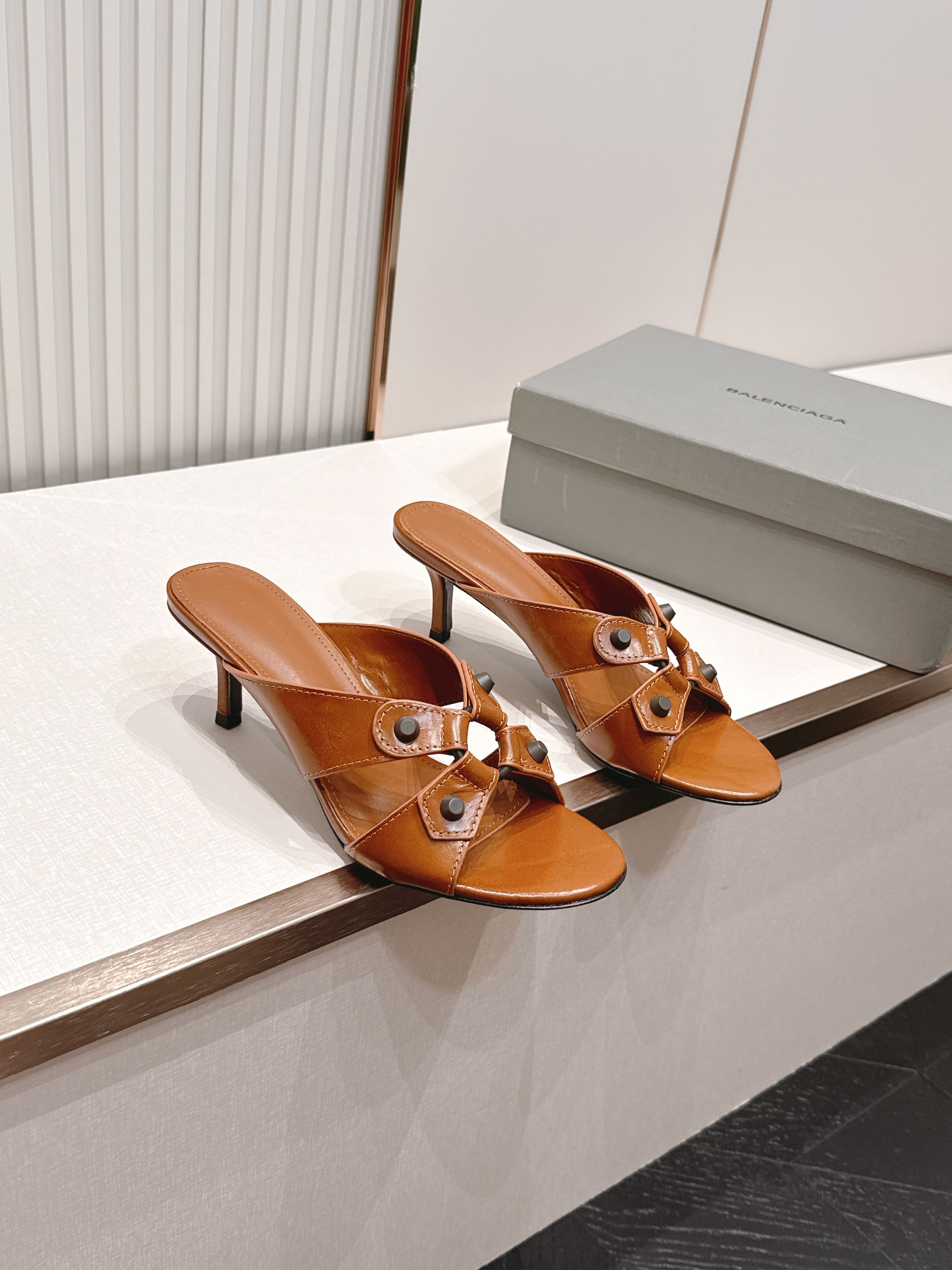NO:868153,P Balenciaga. Balenciaga 26ss spring and summer new rivet hollow high-heeled sandals  The neat open-toe square toe cut has a neat and high-end texture. The classic cross-cut hollow straps are embellished with metal rivets. It has a sweet and cool retro feel. It is full of design. It bids farewell to the monotonous basic style. It has a unique and eye-catching upper. The heelless lazy sandal version is super worry-free to put on and take off with one foot. You can step on it when you go out, and you can wear it lazily and casually.  Moderate high-heeled design, quietly heightening the body shape, elongating the proportion of the legs, optimizing the leg lines, visually making the body appear slimmer and taller, walking steadily and elegantly, and can be easily controlled by novices. Butter leather upper, butter leather lining, heel height 6.5cm, genuine leather outsole, size 35-41 (customized sizes 40 and 41 are non-returnable), high heels and slippers, balenciaga, balenciaga, high heels, slippers, Leather soles19860909P Balenciaga. 巴黎世家 26ss春夏新款铆钉镂空高跟凉拖 利落大气的露趾方头剪裁,自带利落高级质感,经典交叉镂空袢带搭配金属铆钉点缀,甜酷复古感直接拉满,设计感十足,告别单调基础款,上脚个性又吸睛.无后跟懒人凉拖版型,一脚蹬穿脱超省心,出门随踩随走,慵懒随性拉满. 适中高跟设计,悄悄拔高身形、拉长腿部比例,优化腿型线条,视觉显瘦显高挑,走路稳当优雅,新手也能轻松驾驭. 鞋面牛油皮 内里牛油皮 跟高6.5cm 大底真皮大底 size35-41码（40、41码定制不退换）,高跟鞋拖鞋,balenciaga,balenciaga,high heels,slippers,Leather soles,Women's Shoes