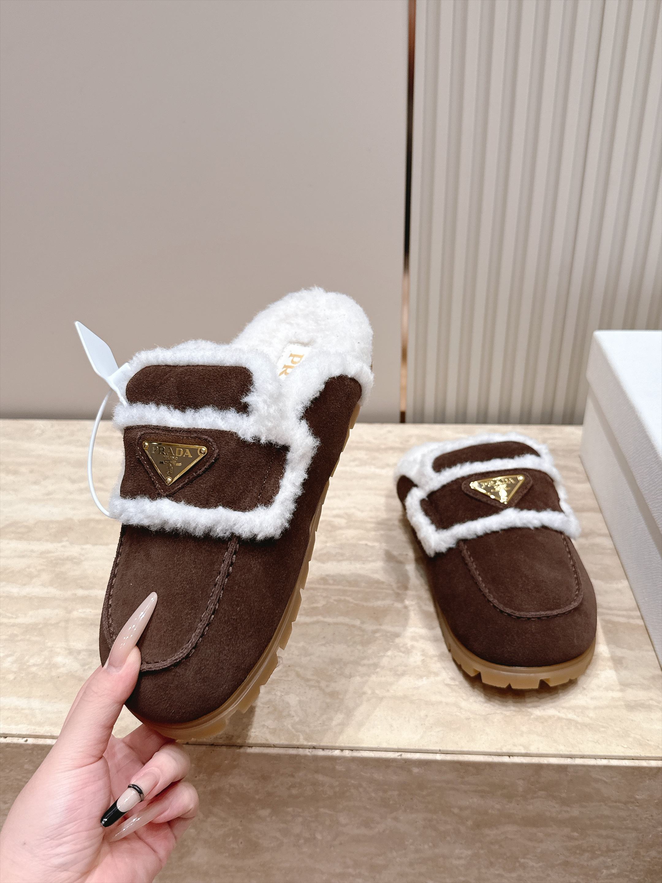 Prada 普拉达 26 秋冬三角扣复古包头半拖毛拖 这双毛拖无疑是先锋美学与慵懒格调的惊艳融合。标志性的三角扣以利落线