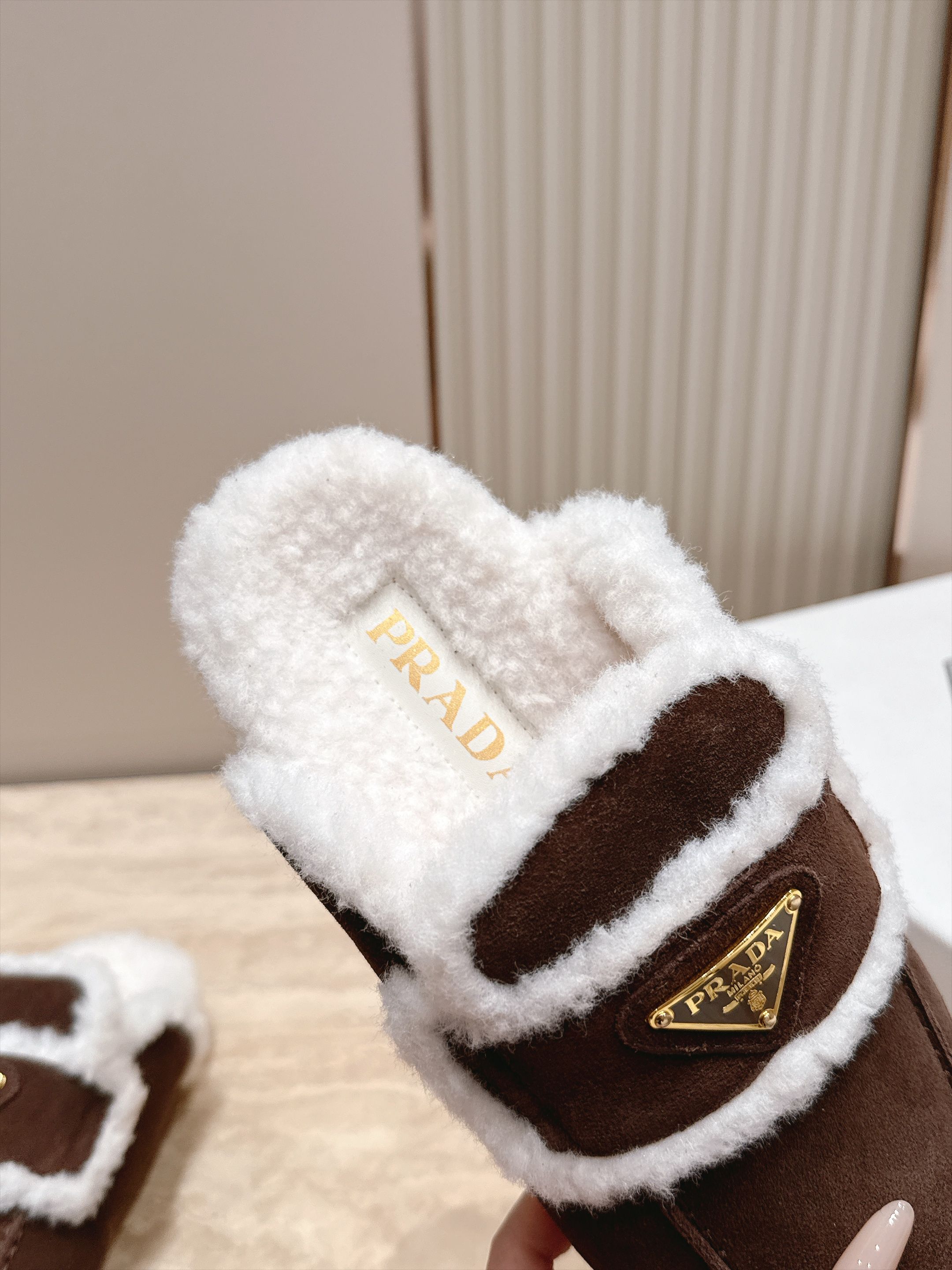 Prada 普拉达 26 秋冬三角扣复古包头半拖毛拖 这双毛拖无疑是先锋美学与慵懒格调的惊艳融合。标志性的三角扣以利落线