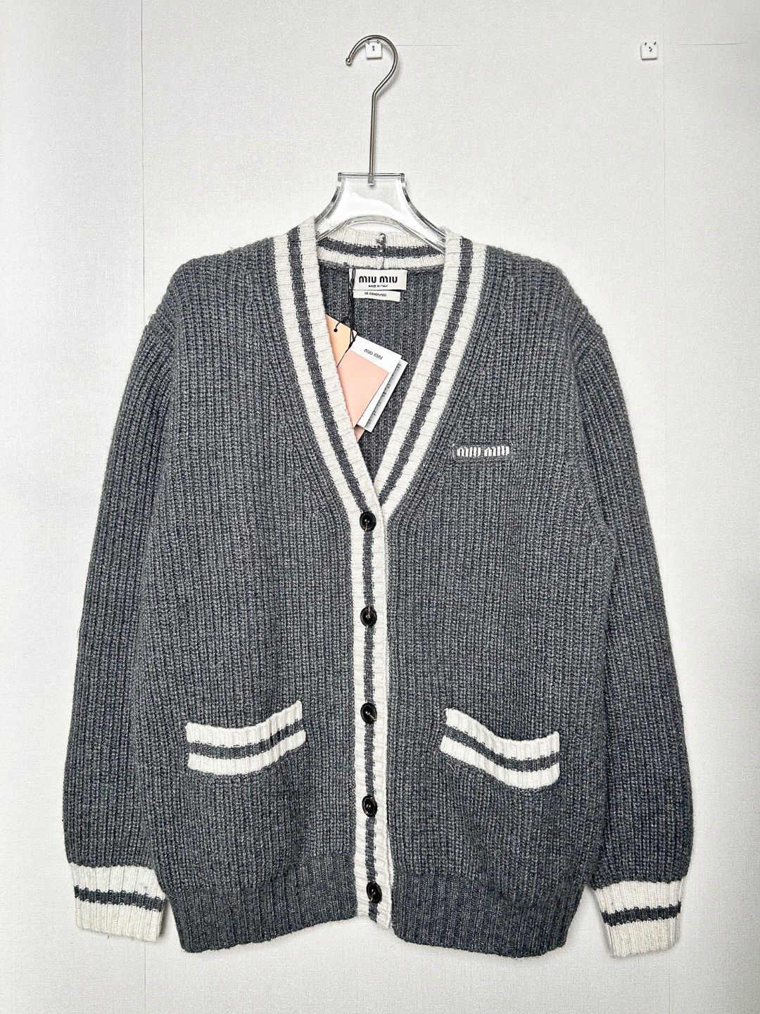 1:1高版本(可扫码) 原版开货 市场唯一对版 MIUMIU - 慵懒学院风撞色V领开杉针织羊毛衫上衣 明星同款 MIU家的经典学院风真的是无人能抵抗的 100羊毛 高品质 不同于市面上的low货 懂货的来 钩花字母V领单排扣针织开衫 领口袖口包边条纹 搭配经典灰白配色 精致亮眼感拉满 胸口拉花字母装饰 腰胯对称口袋设计 强力推荐!!! 码数SMLXL 价格249