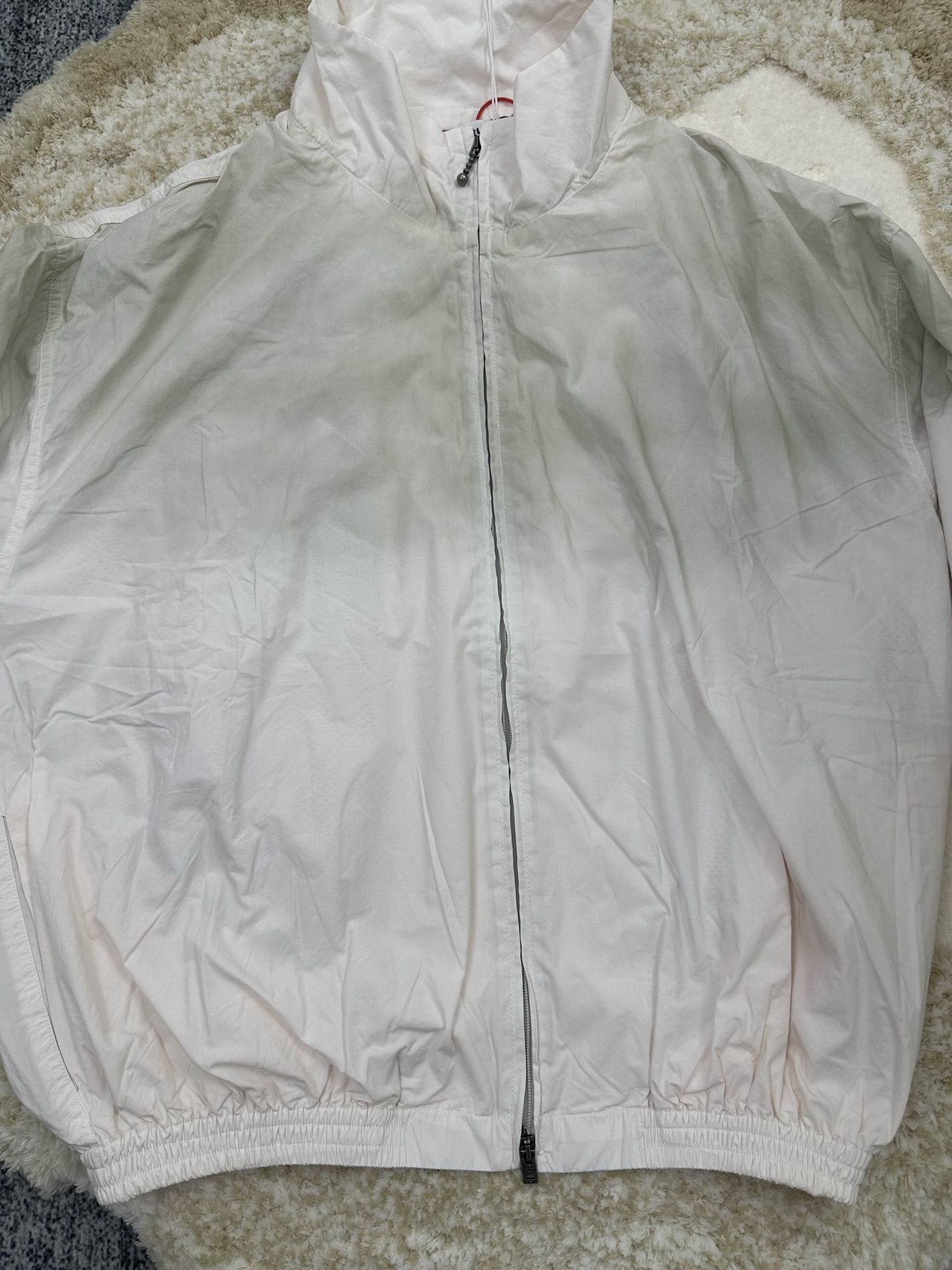 P290,全网顶级版本
Acne Studios 撞色徽标拉链夹克

定制幻光雅棉细织绸 柔软丝滑 舒适贴肤 以泛黄的米白为色调 那不经意间晕染的做旧效果 邂逅复古情怀载体 幅饰以同质化展示 搭配后幅醒目的 Acne Studios 1996撞色徽标点缀 既有着复古的韵味 又散发着现代的简约时尚感 松紧袖口和下摆设计 巧妙地勾勒出身体线条 在随性中透露出无法忽视的高级感 是街头最具格调的时尚先锋

采用固体印花 胸前印花经过三次菲林网板修改 使用胶浆液体涂料在织物上打印图案 烘烤织物以固定印刷图案

渐变做旧喷马骝工艺 通过在织物表面喷洒不同颜色的染料 实现衣物在不同光线下呈现出丰富的色彩变化 增加视觉层次感

重度孝洗 通过特制溶液 去除污渍且轻微的褪色 再雪花洗 通过强烈的洗涤方式来褪色 使其颜色更为均匀

下摆采用三针像筋拉腰机一次而成 利用机器的特殊针位和送料机构 将松紧带与布料在同一工序中缝合在一起 三针的设计更加牢固 能够均匀地分布压力 确保松紧带与布料紧密贴合
尺码： 42 44 46 48